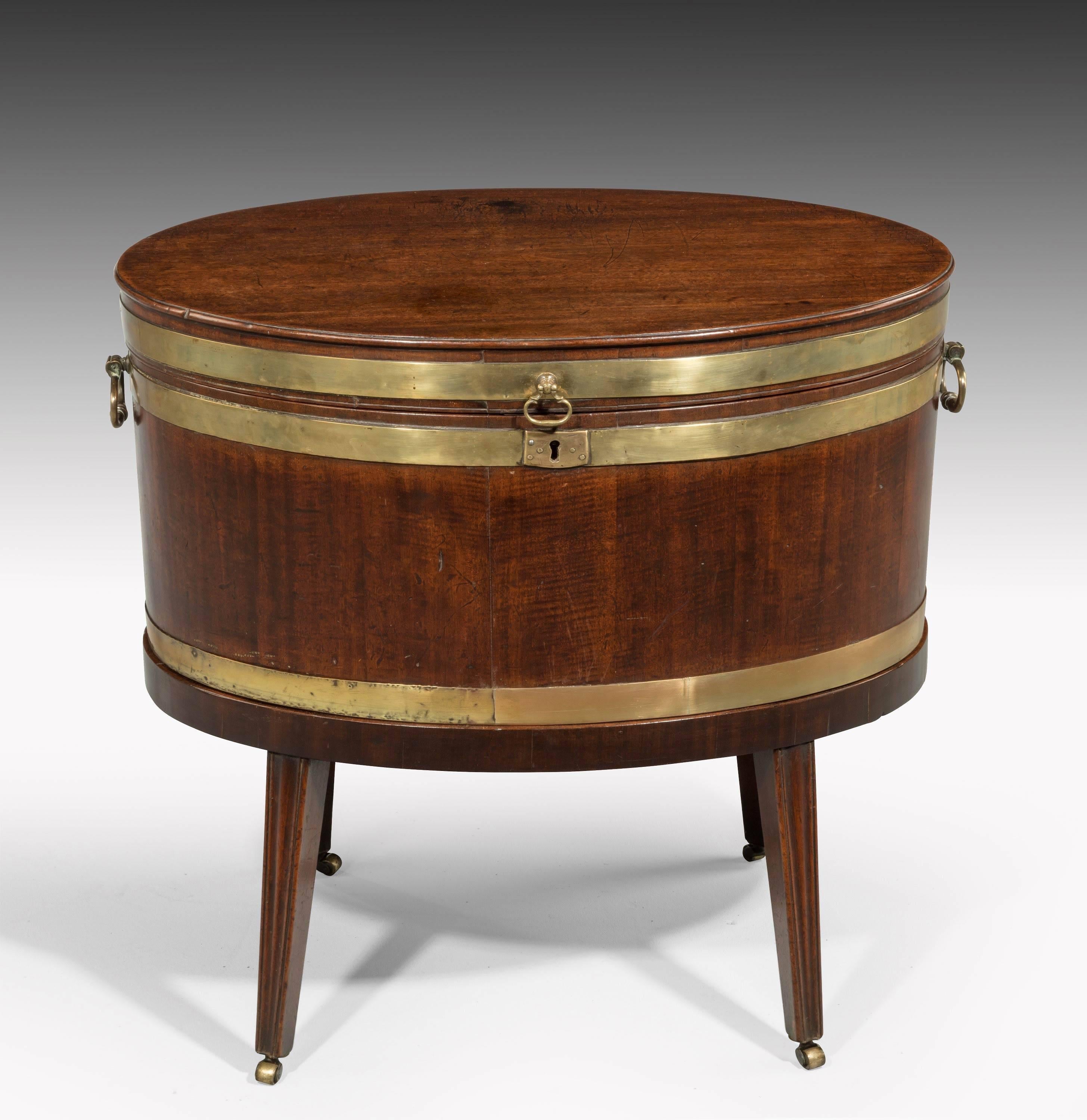 George III period mahogany oval brass bound wine cooler of finely shaped reeded tapering supports. The interior now entirely missing.