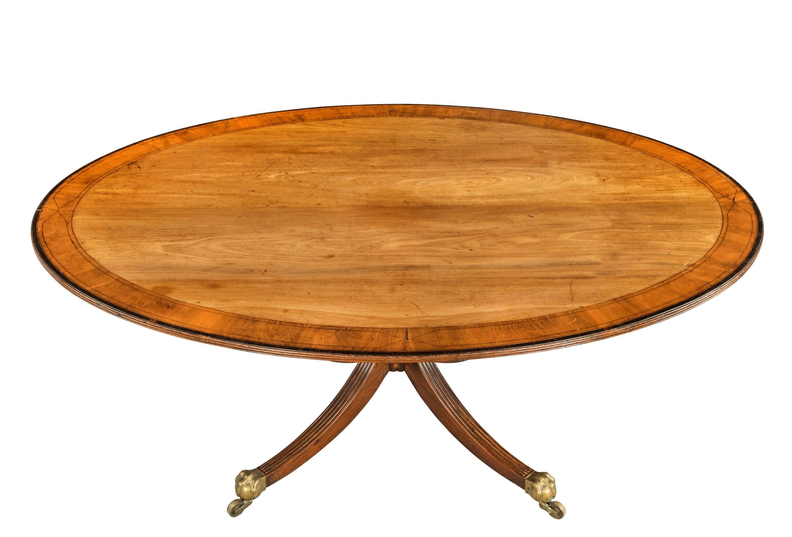 A fine large oval mahogany breakfast table. The beautifully figured top very broadly crossbanded with line inlay. Turned central support. 1790 design but actually 1910.