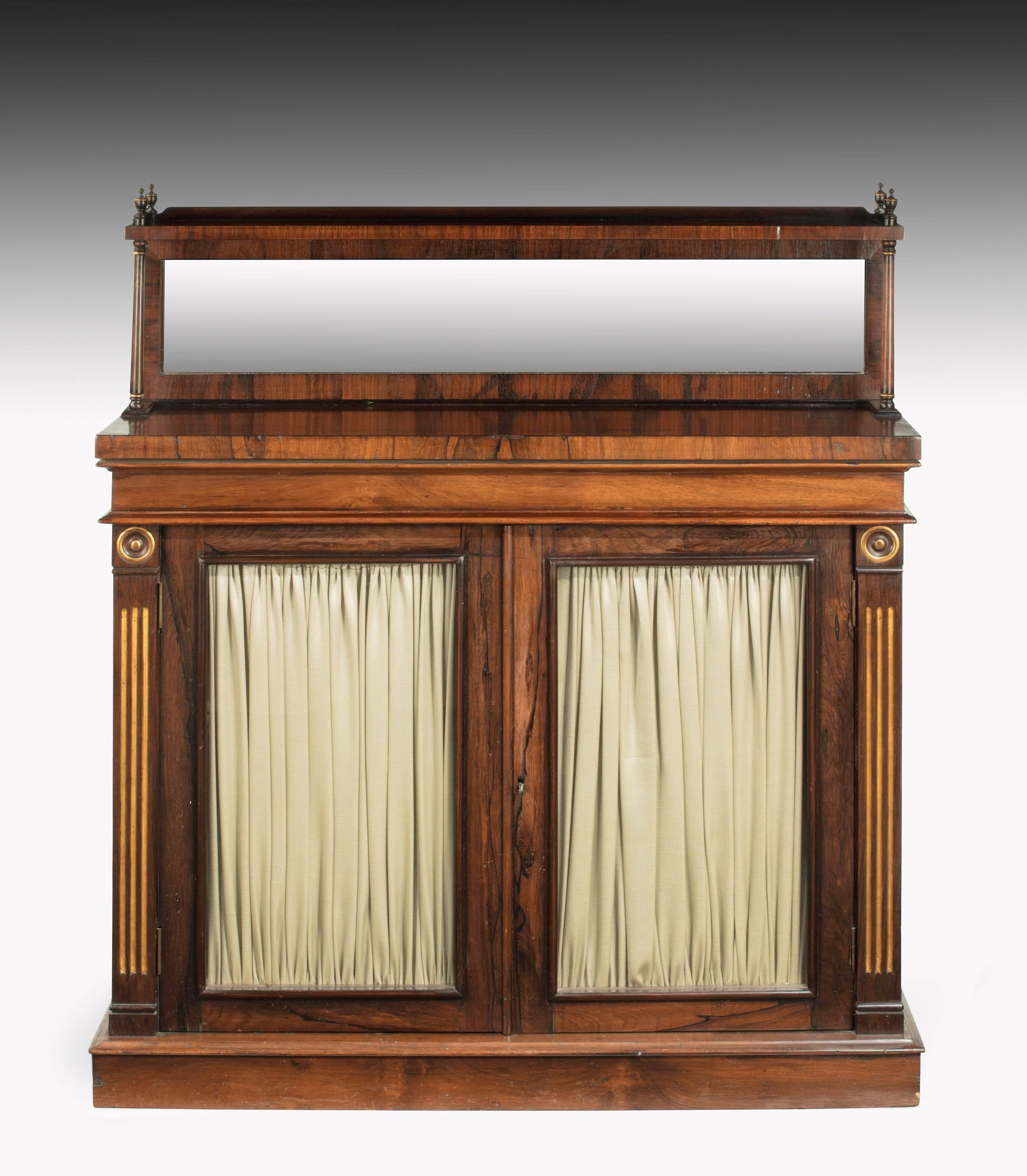 A Regency period mahogany, chiffonier the top section with a mirror. Crossbanded edge. Finely carved uprights to the left and right hand side. Plain glass base drawers.