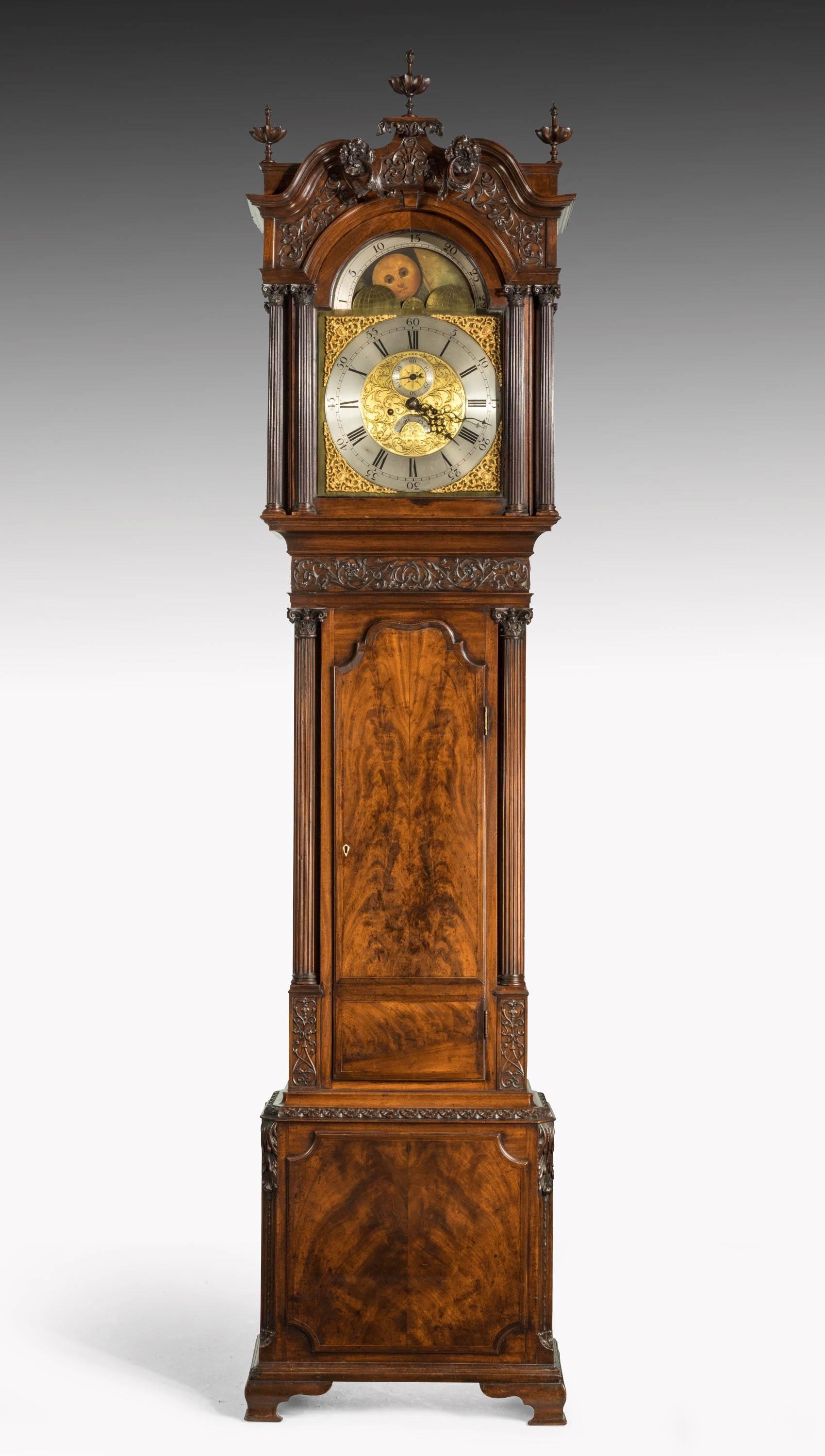 George III period carved mahogany longcase clock by George Monk of Prescot
The scrolling swan-neck carved pediment with flame finials above an arched glazed door flanked by double Corinthian carved columns to each side, above a scrolling acanthus