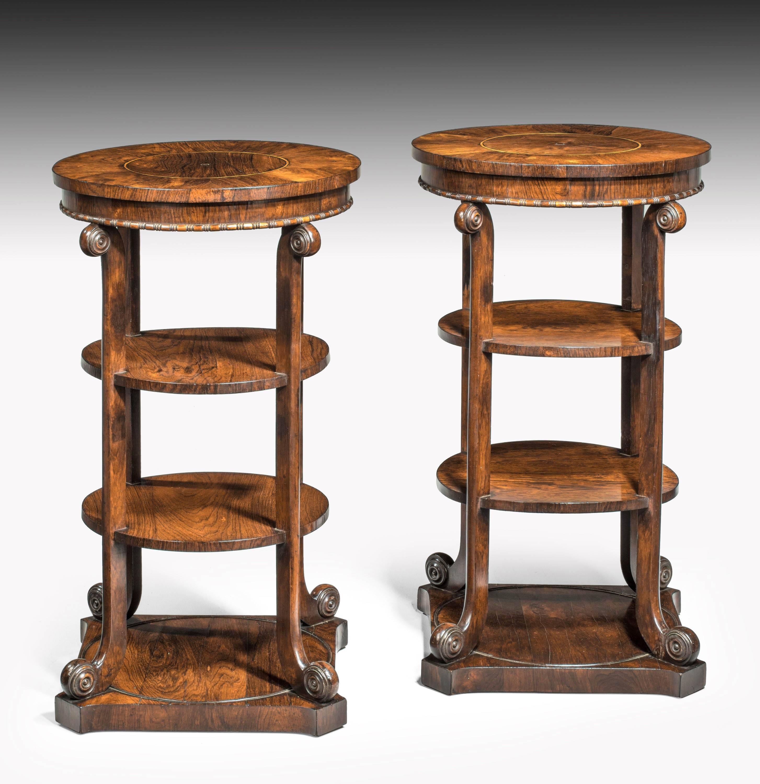 A most unusual pair of Regency period mahogany etageres of finely figured timbers. The circular tops very broadly crossbanded in flared mahogany. The supports shaped top and bottom on platform bases.