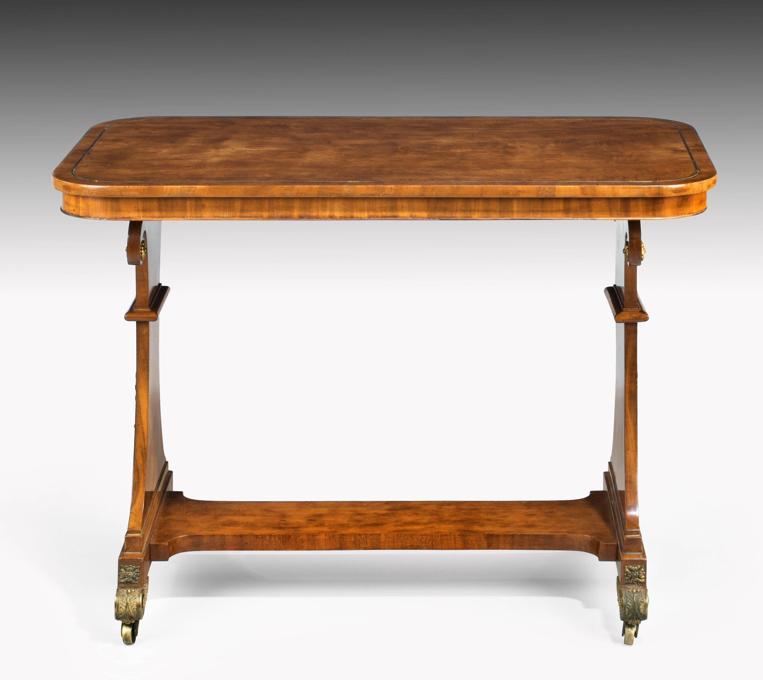 A very elegant and finely figured Regency period satinwood end support table. With the original satinwood foot rest. Beautifully figured ormolu mounts to the ends and finely cast ormolu shoes. A single brass inlay to the top and edging to the base