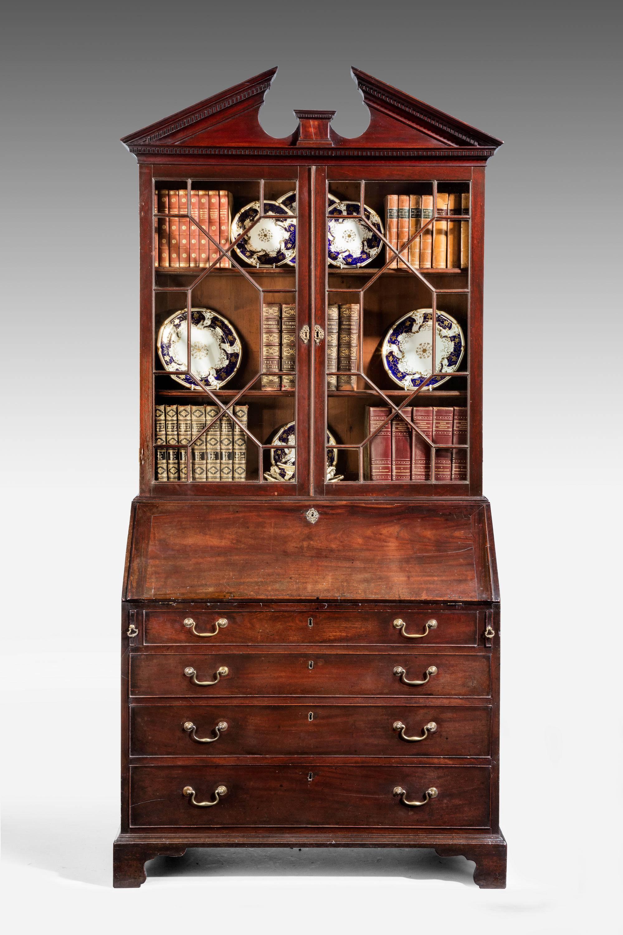 A George III period mahogany bureau bookcase with associated glazed top of the same period. The top with a broken arch pediment and good quality glazing bars. The base of the bureau beautifully fitted with numerous pigeon holes, drawers and four