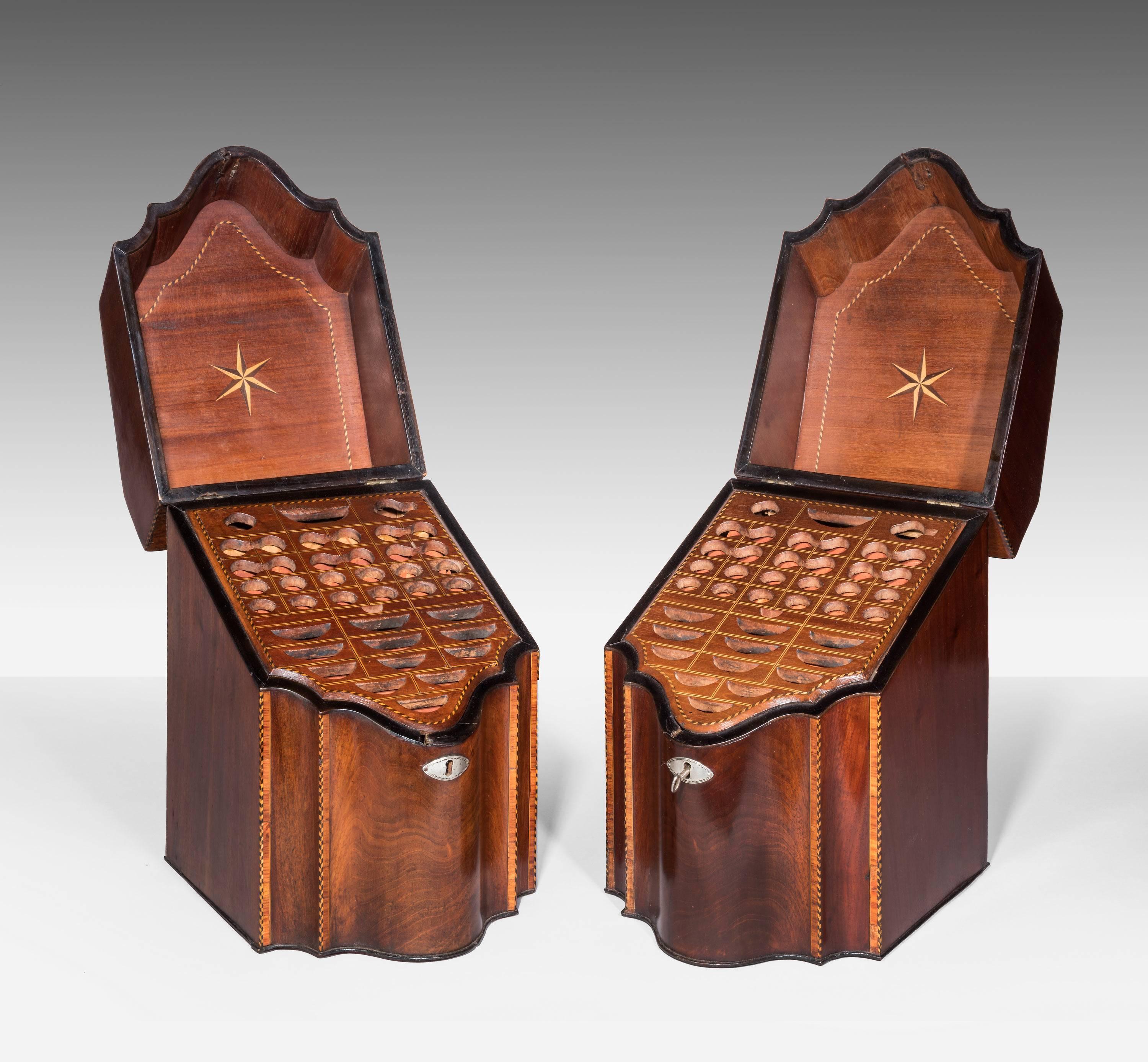 A Fine Pair of Double Serpentine Mahogany Knife boxes. Retaining their original fitted interiors.  The whole with a chequered edge inlay and within that frame work fine cross banded Indian wood. Excellent overall condition. Retaining original oval