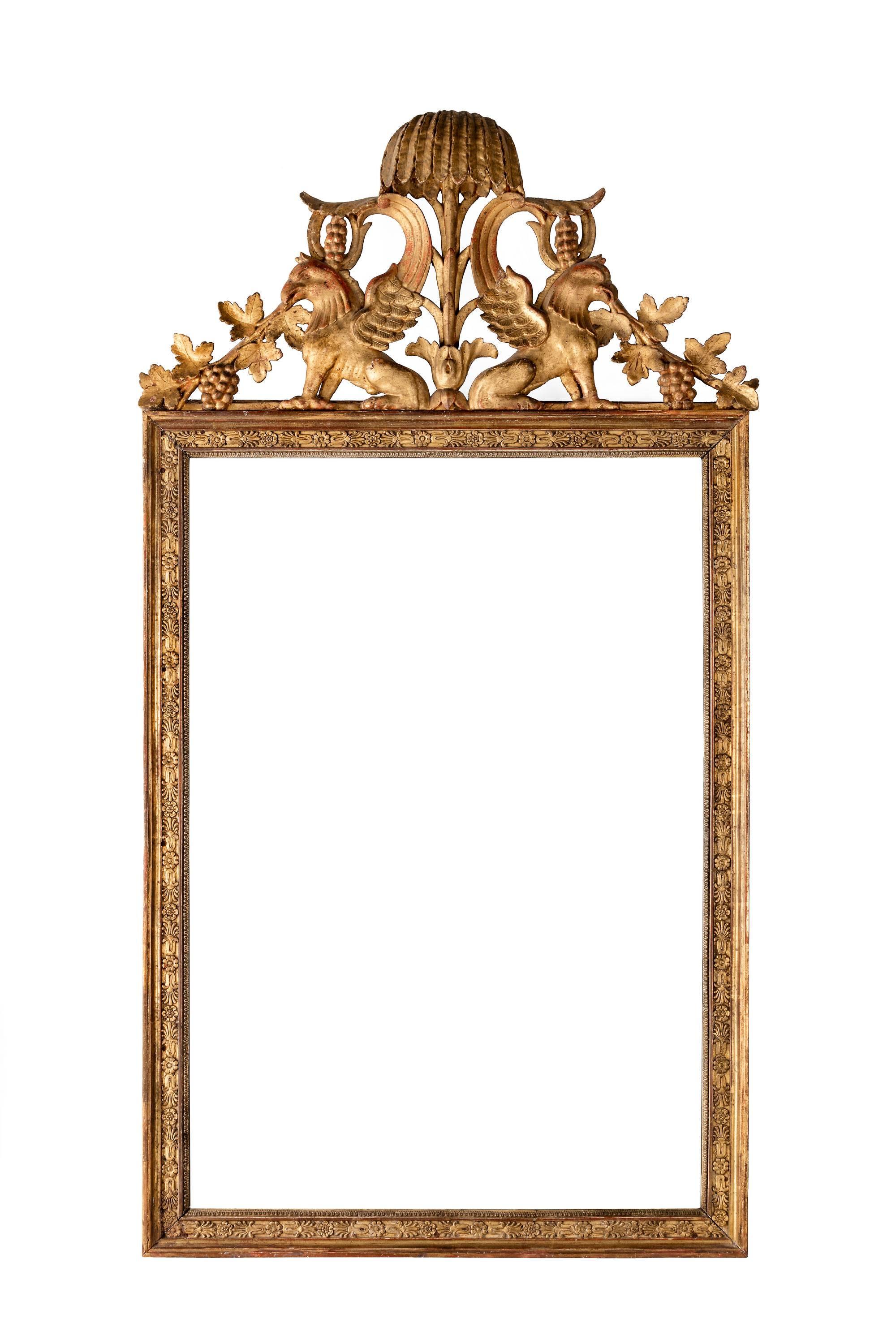 A most attractive Continental mid-18th century giltwood mirror. Inset carved border. The top with fabulous beasts within a stylized palm tree. Original gilding somewhat tired, and with a lovely original plate.