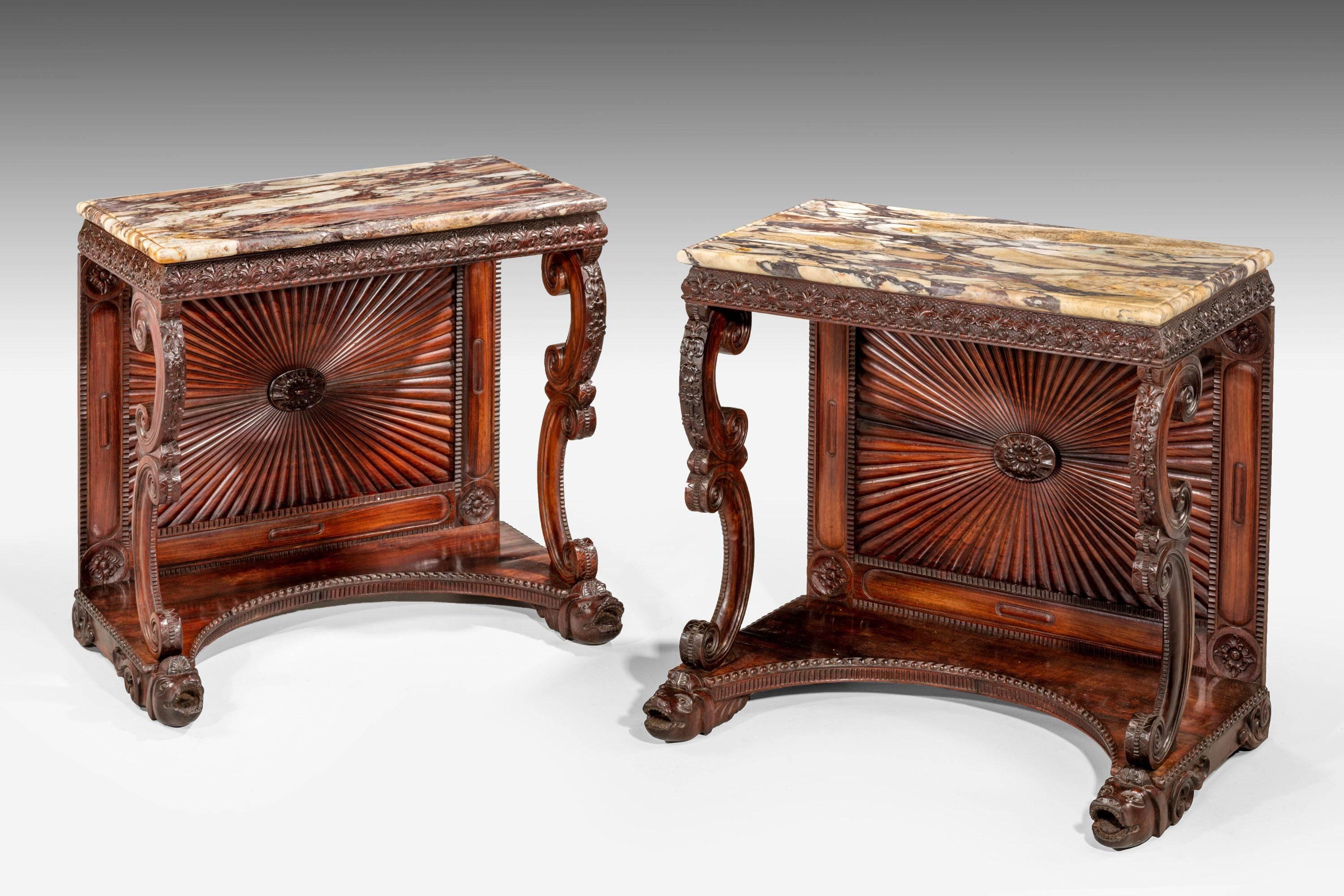 A very finely carved pair of Regency rosewood pier tables, with elaborately scrolled front supports. The borders of extended fleur-de-lys design. Concave platform bases in front of beautifully carved radiating back boards. The whole of the highest