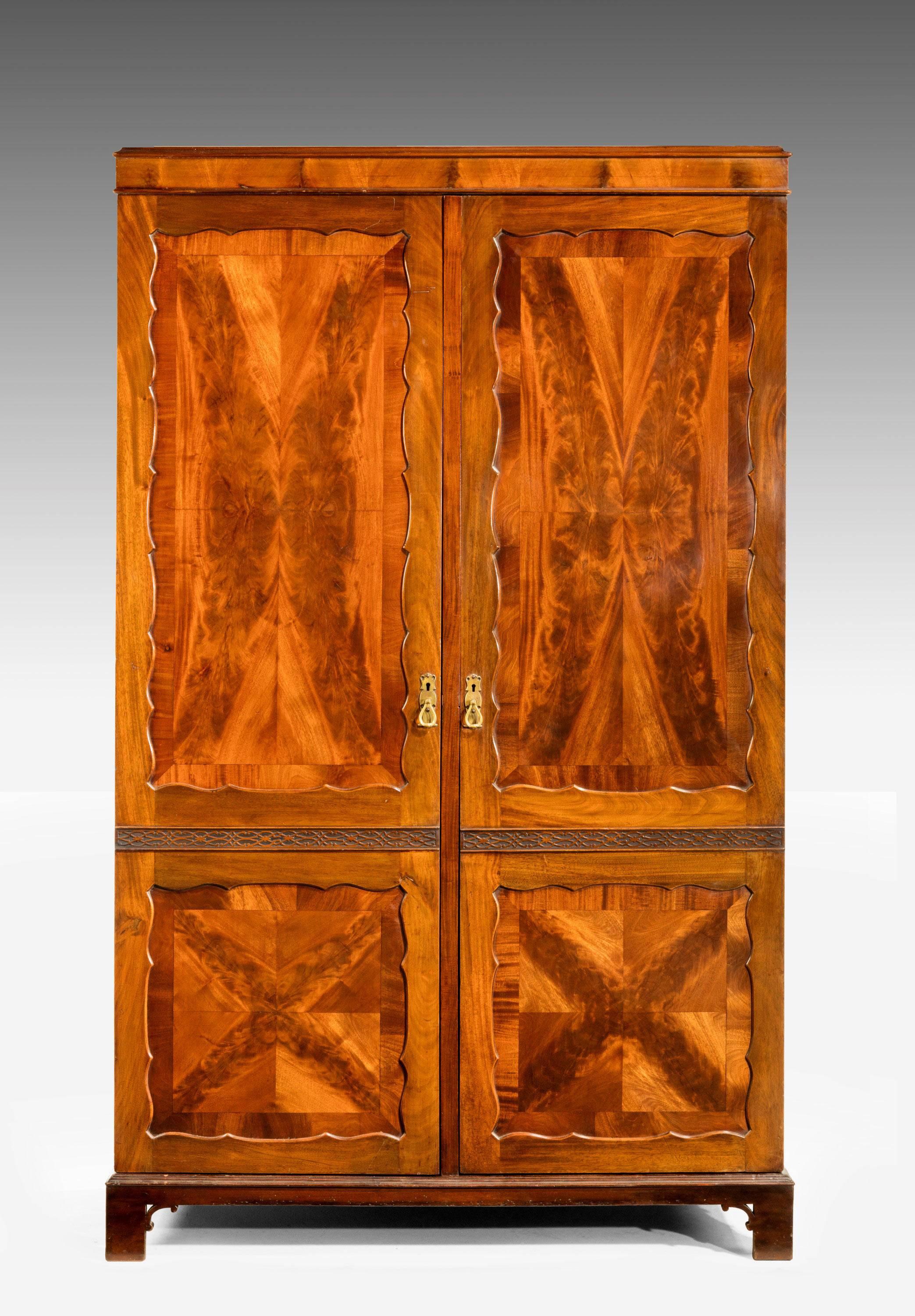 A very finely figured mahogany two-door wardrobe. With blind fret sections to the front. The Timbers book leafed. Paneled doors with wavy surrounds.