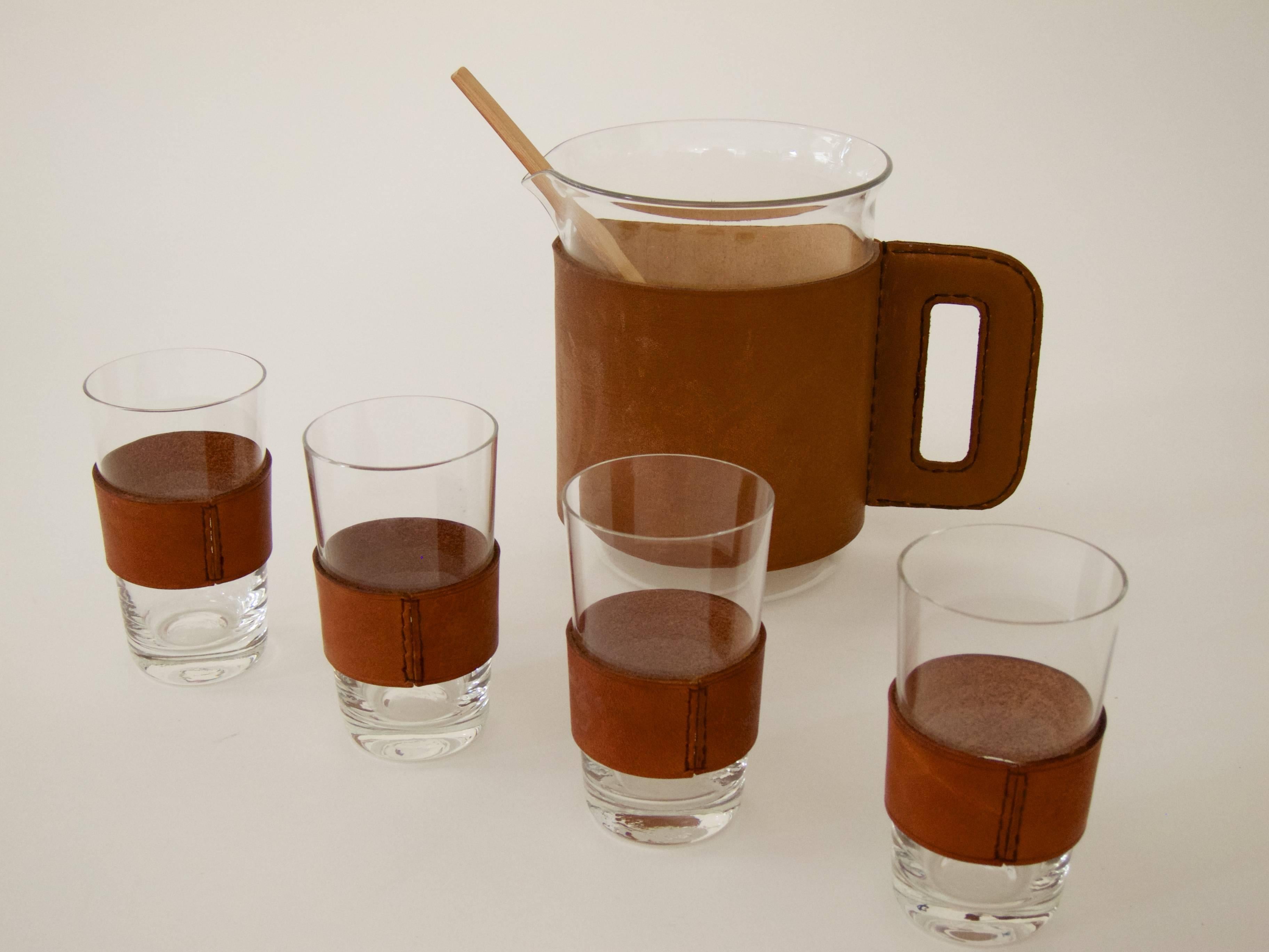 Set of pitcher with four Glasses and a bamboo muddler
Handblown glass, leather sleeves (with a leather handle on the pitcher), bamboo muddler
Great condition with nice patinated leather.

Pitcher Ø 11.5 cm, H 14.5 cm
Glasses Ø 5.5 cm, H 9.8