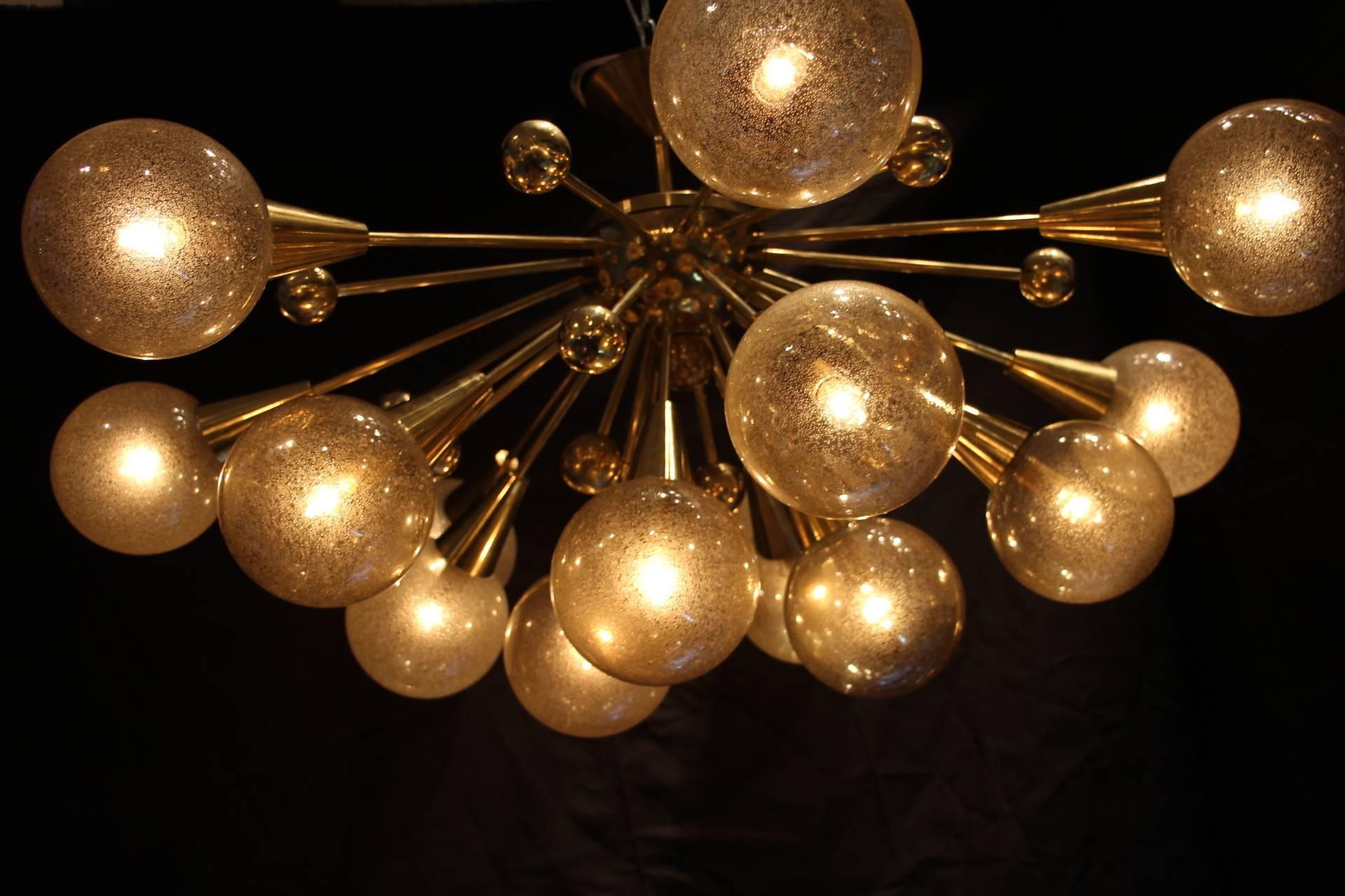 This brass chandelier features 15 champagne Murano glass globes and 15 brass balls extend on brass stems from the center. Each globe has got golden glitter inclusions.
Warm and pleasant light.
Unusual proportions: Only 65 cm height and 105 cm