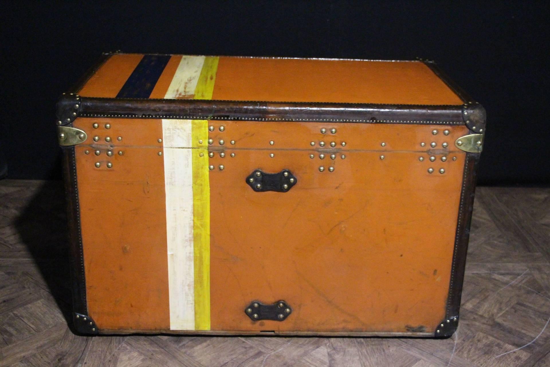 This unusual orange Vuittonite canvas courrier trunk has got all leather trim and handles, brass corners, all brass stamped LV studs and brass locks; it has a beautiful warm orange patina.
Its interior is original with beige linen except under the