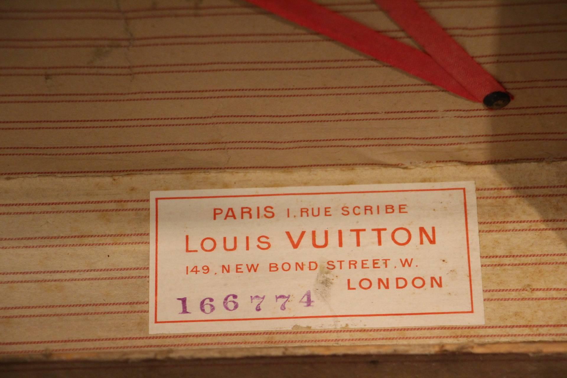 This unusual Louis Vuitton hat trunk features black canvas, silver steel trim, black steel lock and side handles.
Brass stamped Louis Vuitton studs.
Travel labels.
Its interior is original with its white and red lines lining and its removable
