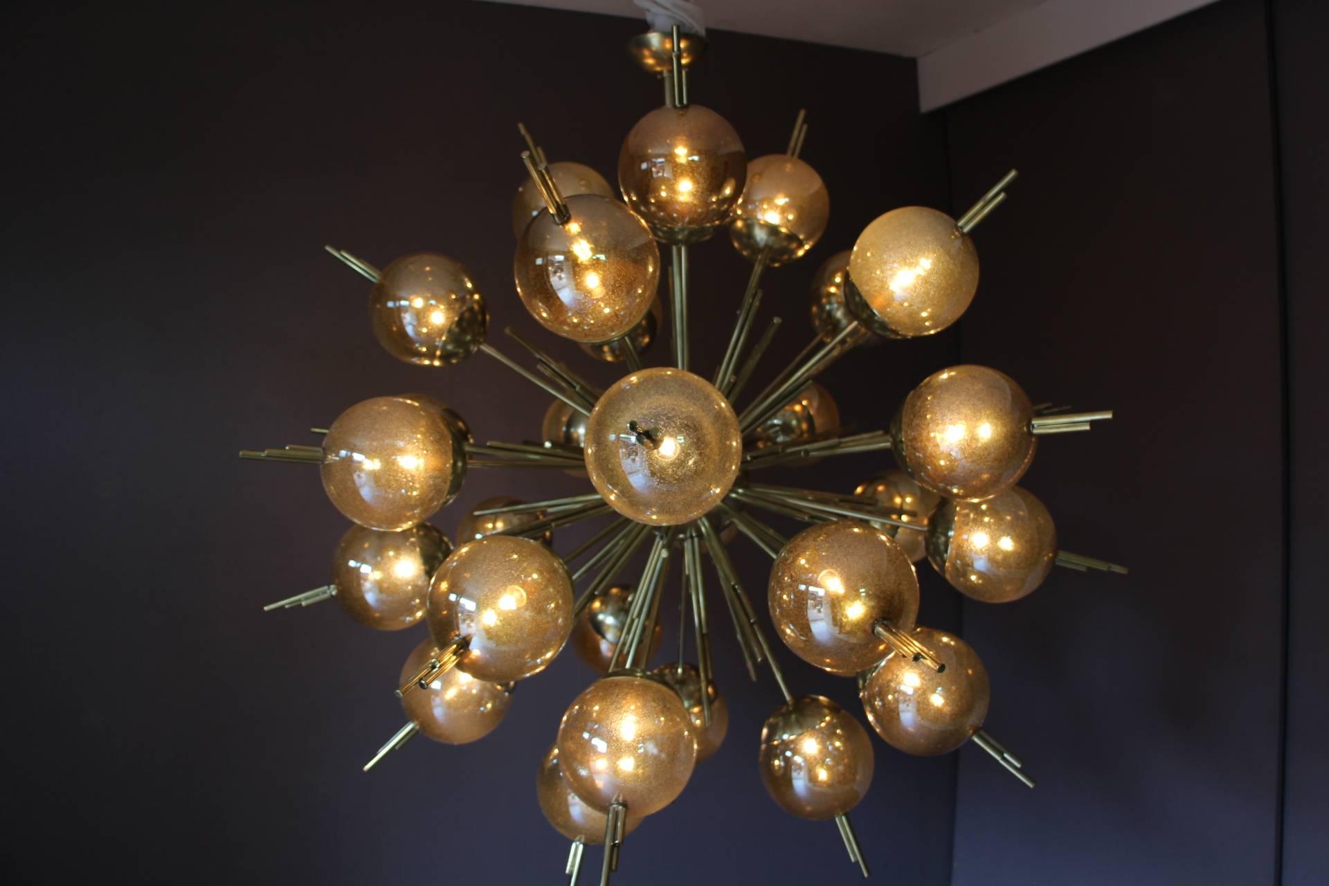 This very chic chandelier features 30 golden glitters glass globes mounted on brass rods.
When light is on glass globes show golden glitter inclusions and when it is off, they become mercury color.
It is very elegant and impressive.
Warm and