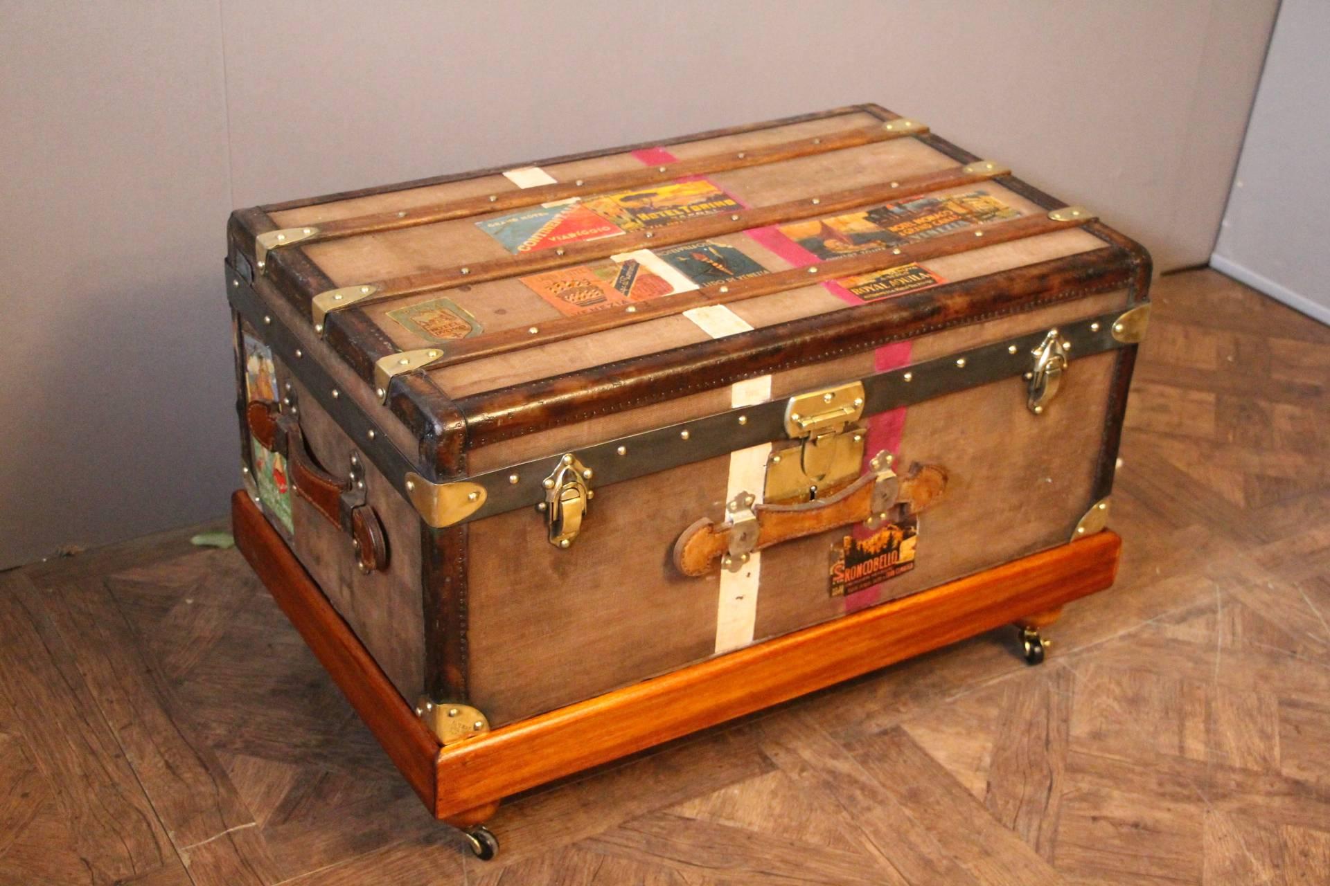 This nice steamer trunk features brown canvas, leather trim and side handles and brass corners and locks.
Many travel labels and white and pink stripes of customization.
Its main lock as well as its corners are marked 