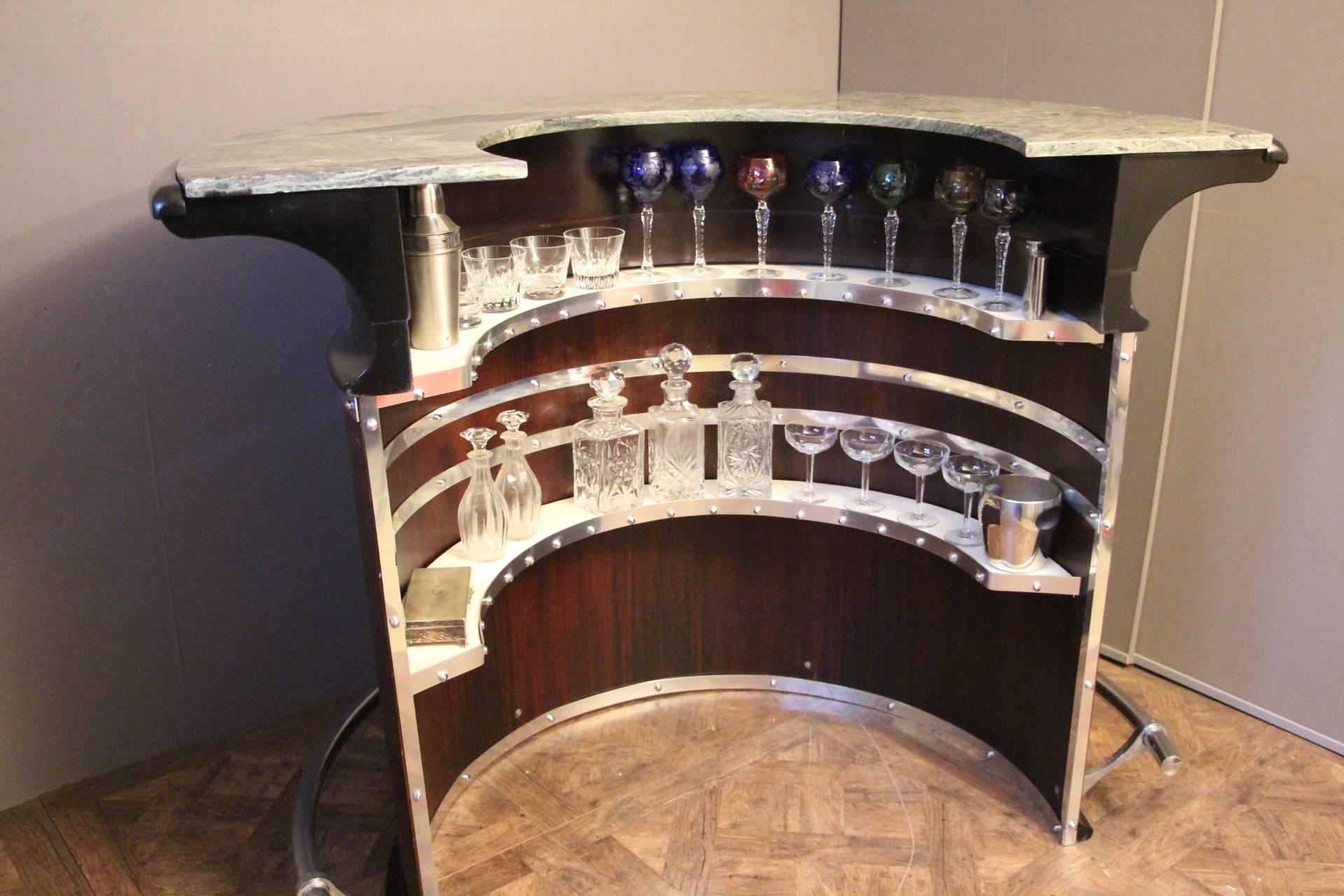 Ce magnifique bar est très confortable avec sa forme en demi-lune, son plateau en marbre vert et ses étagères intérieures.
Il est composé de bois de palissandre, de bois noirci et d'accessoires chromés.