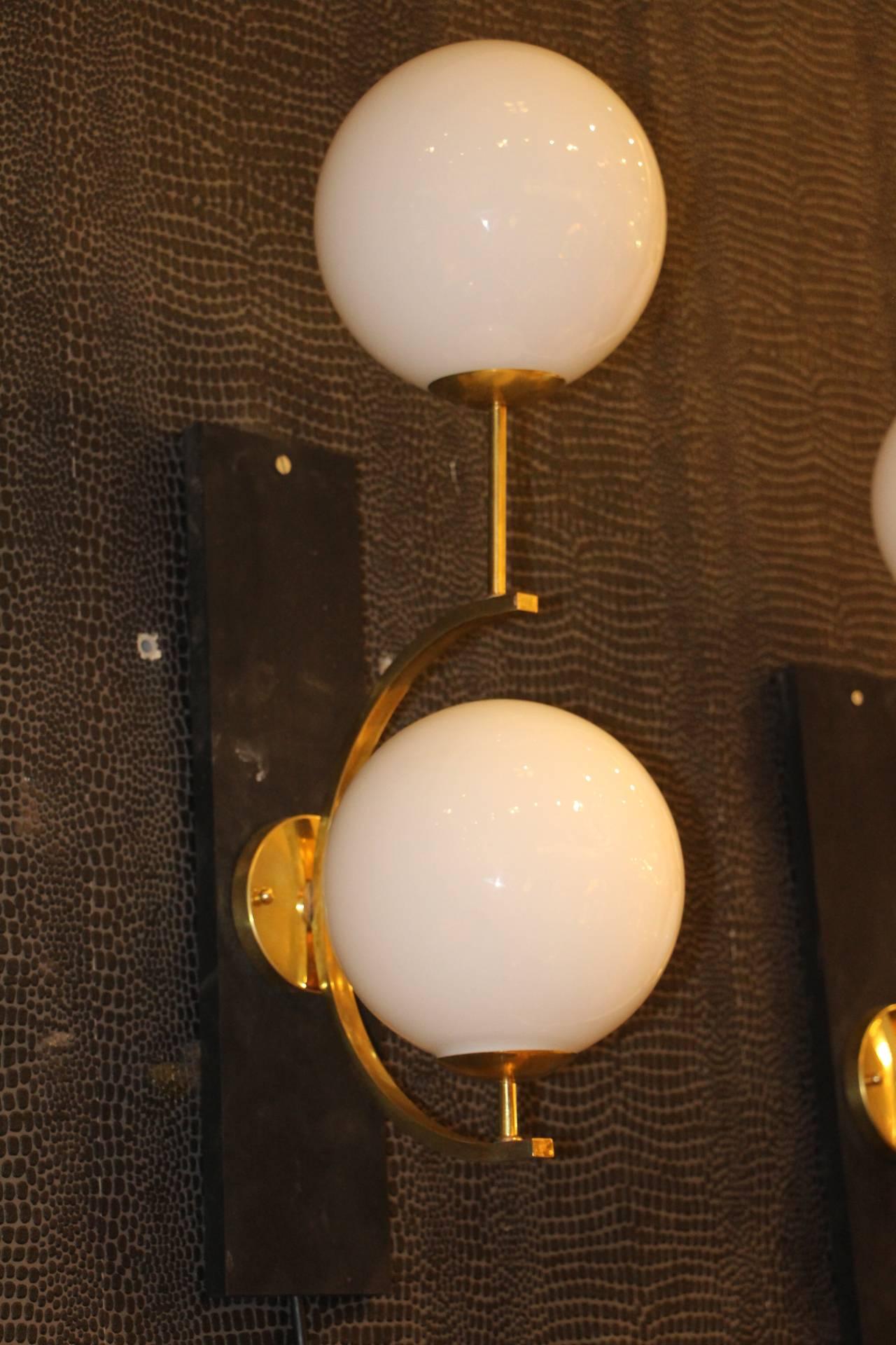 These sconces are very elegant with their brass frame and white Murano glass dome. They have got very unusual geometrical proportions and are very elegant.