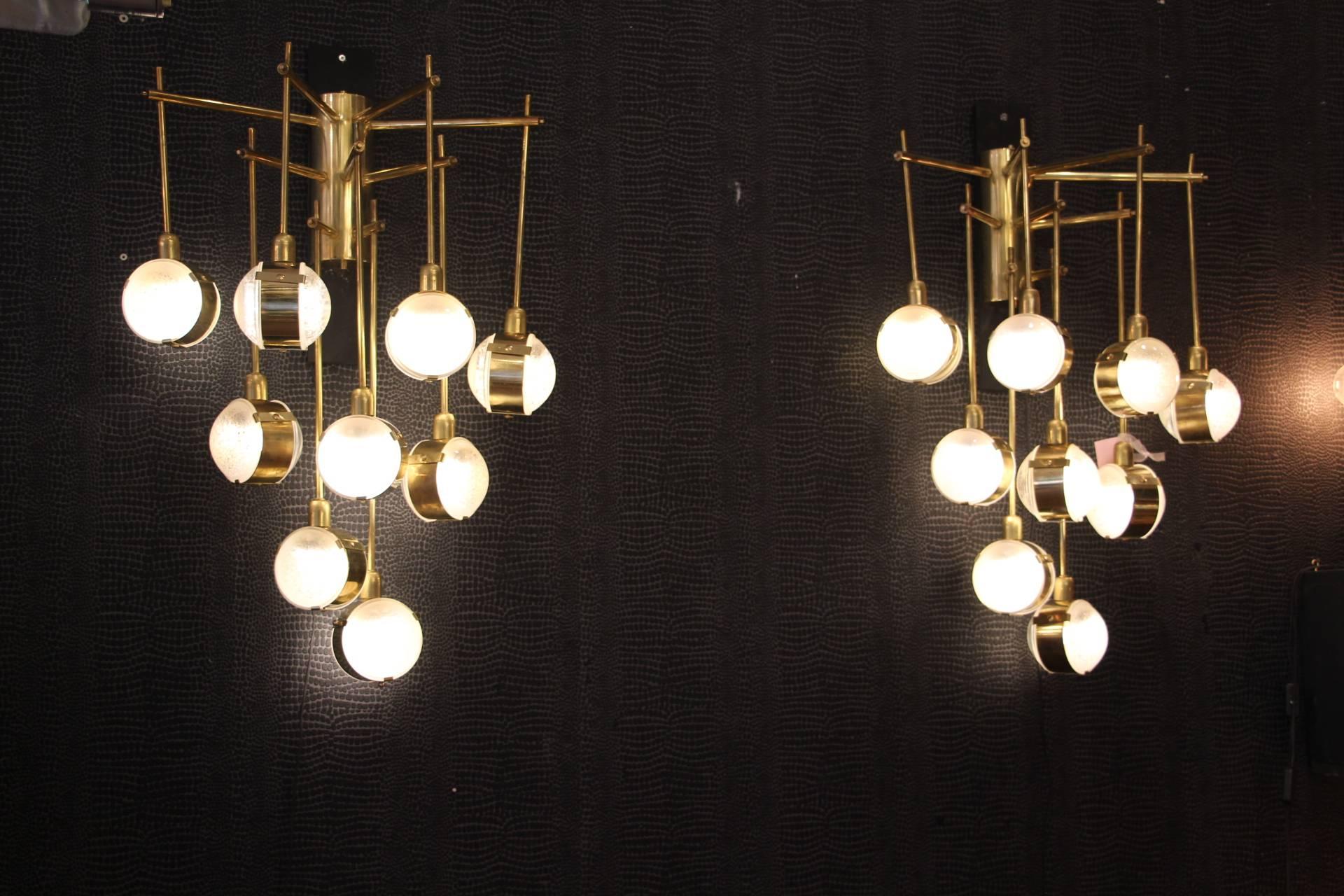This pair of wall lights features nine lights each.
Each vertical arm is finished with a double sided glass, circled in brass ring. All glass pieces gave a lenses shape and show quartz inclusions inside.
These sconces are really unusual and