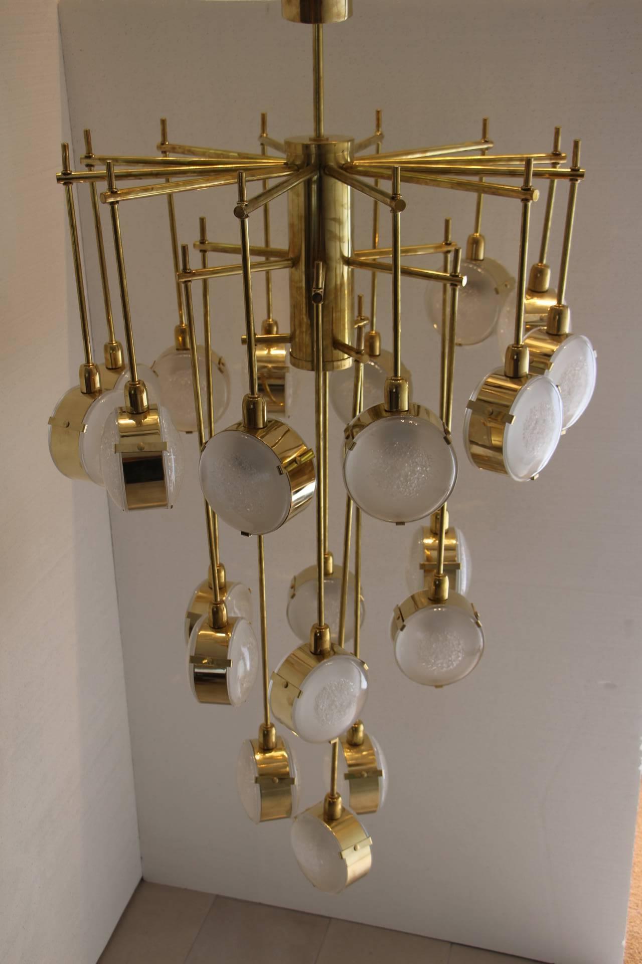 This chandelier features twenty-one lights. It is very unusual shape.
Each vertical rod is finished by a double sided glass lentil circled in brass ring. 
Every piece of glass has quartz inclusions, which make many reflects inside the glass .It is