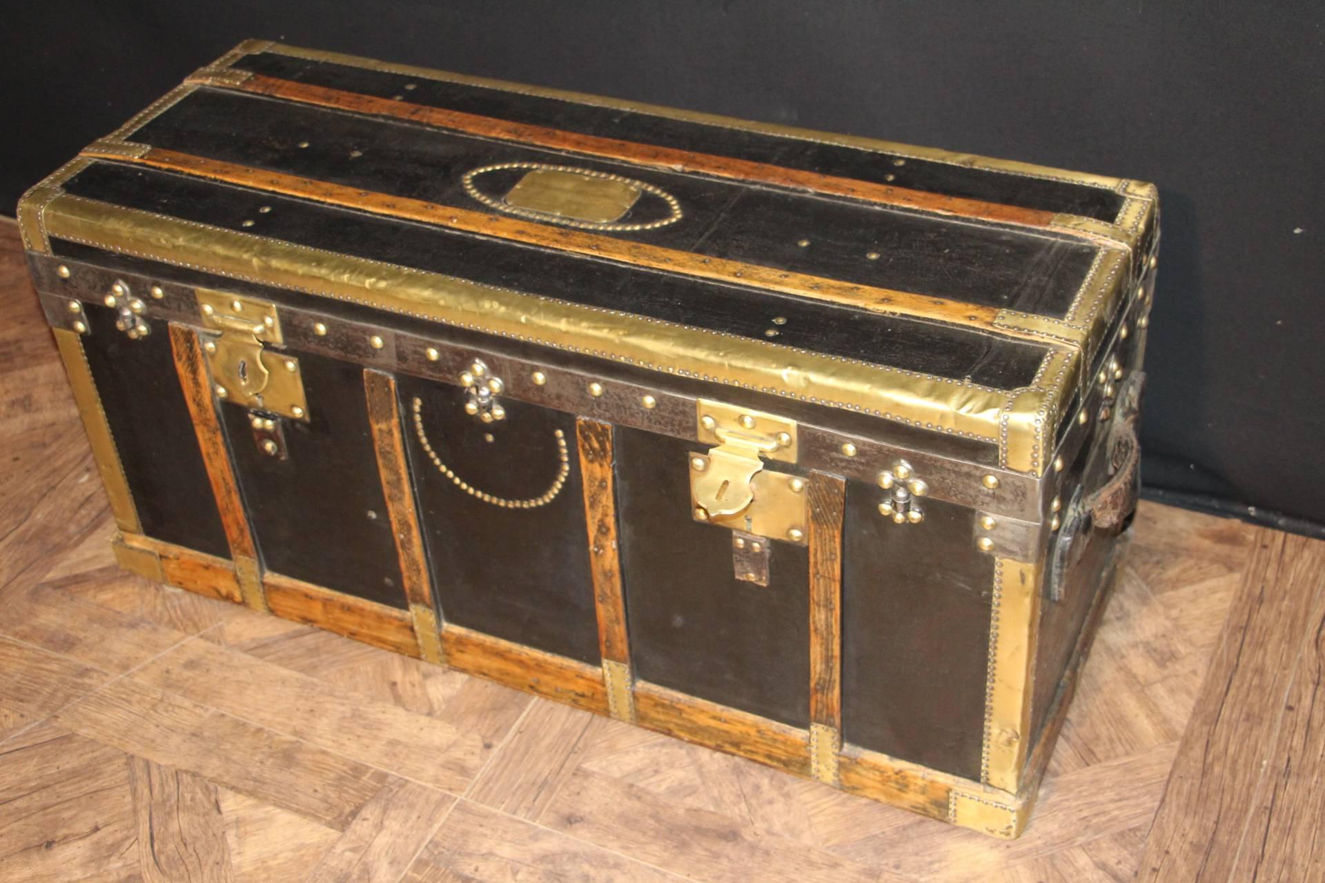 This balck canvas stemer trunk features brass trims,studs and locks as well as wood slats and large leather side handles.
It has got unusual proportions because and it is not deepit ,could be a very nice blanket box.
its interior is all original