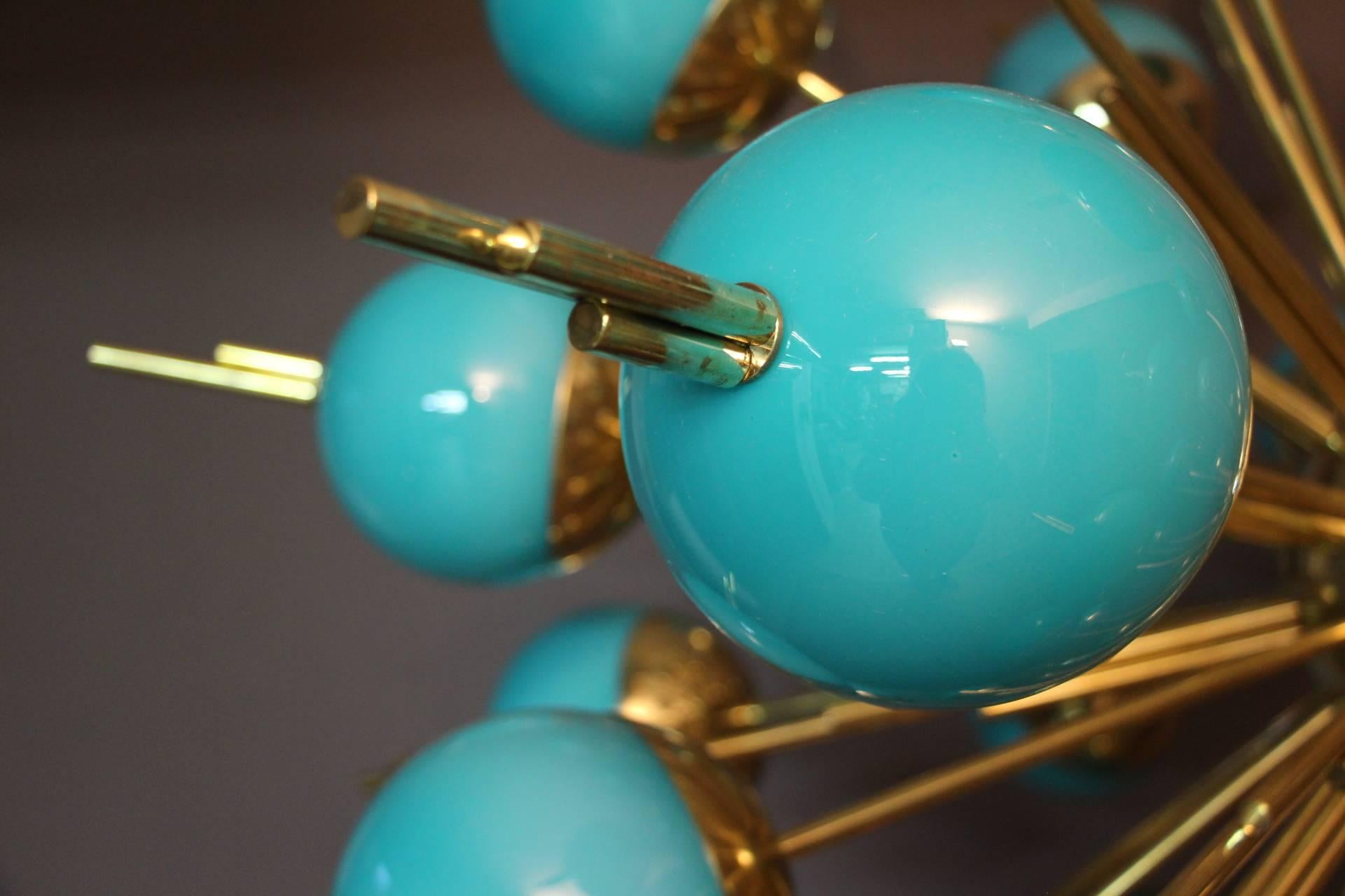 This very unusual Sputnik chandelier features 30 turquoise glass globes mounted on brass rods. When the light is on, its turquoise globes turn to light blue color and it is still magnificent.
