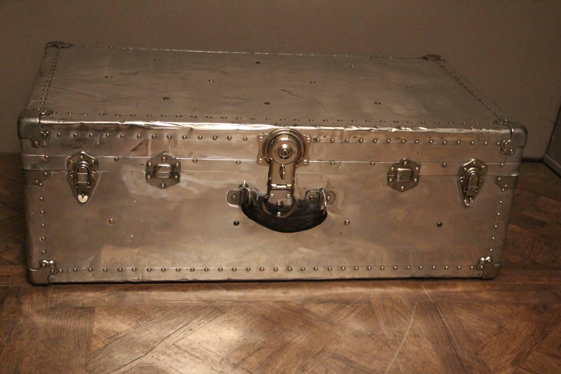 Beautiful mirror polished aluminum steamer trunk featuring steel corners, steel studs, steel locks and leather side handles. This piece of luggage could be a perfect coffee table in all styles of interiors.Leather handles and golden brass studs.
It