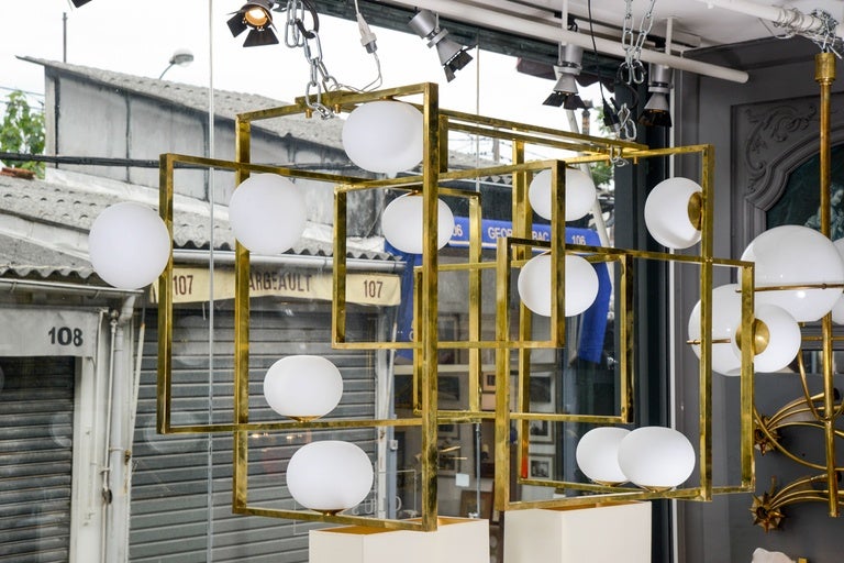 Brass chandeliers made of multiple rectangles assembled and white glass globes.

New design by Glustin Luminaires.