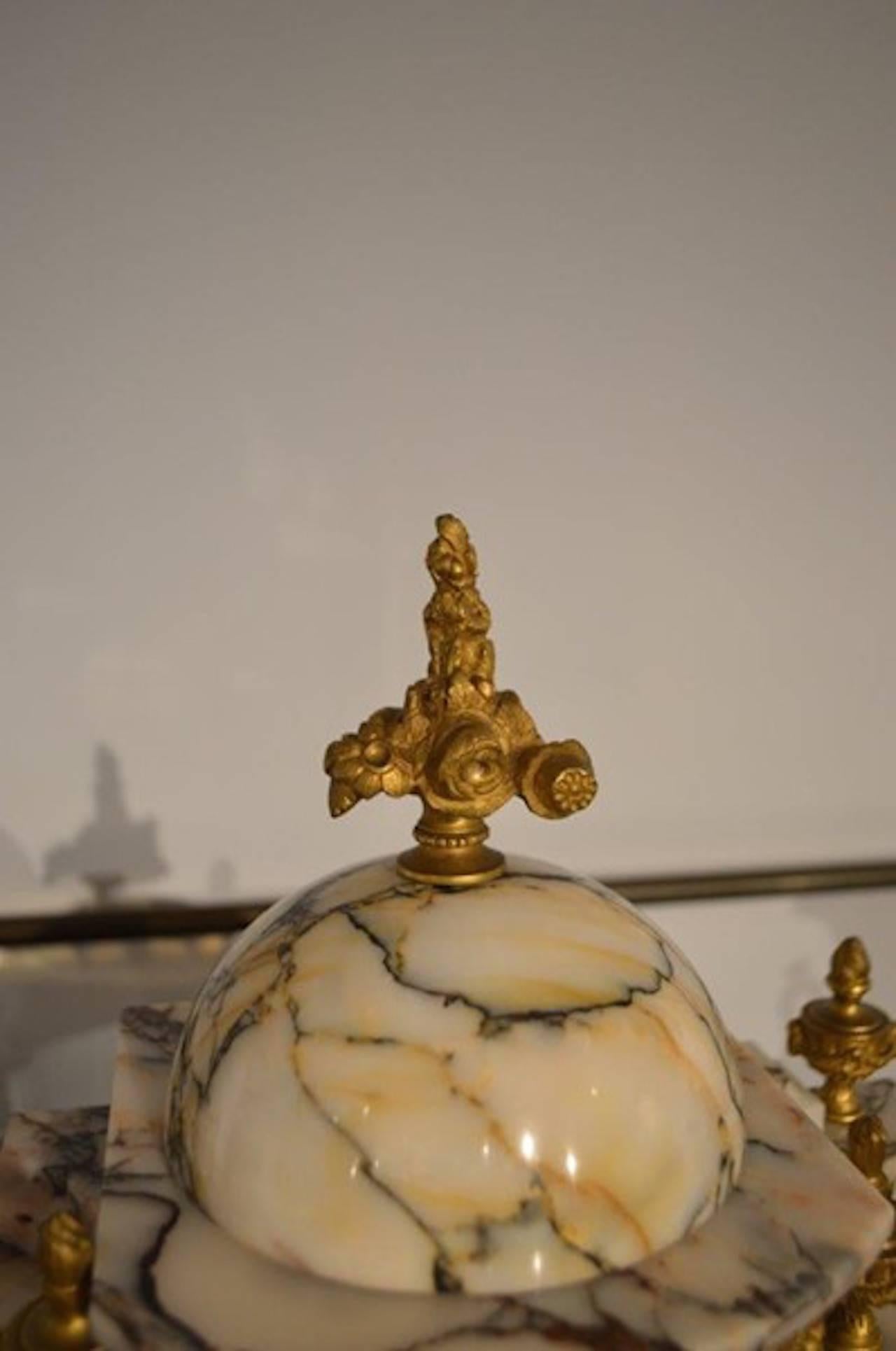  A beautiful French marble & ormolu clock garniture. The domed topped clock with cast ormolu finials raised on marble and gilt bronze Corinthian columns with ormolu taupe feet. The French twin train clock movement having a mercury filled pendulum