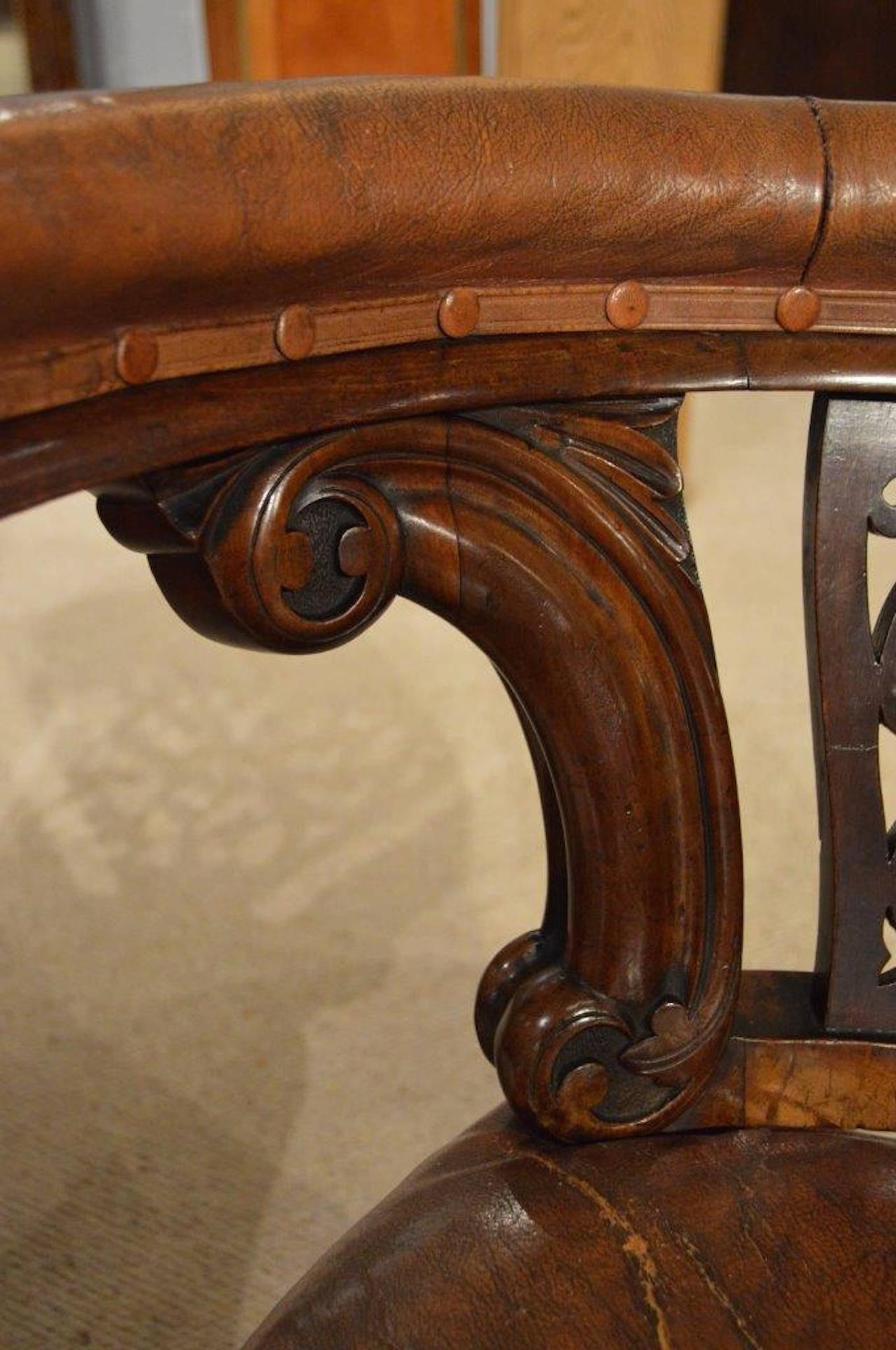 A good and rare pair of mahogany Victorian Period antique desk chairs. Each with a curved back rest upholstered in brown leather with a finely pierced fretwork back panel and carved mahogany supports above a generous sprung seat which is also