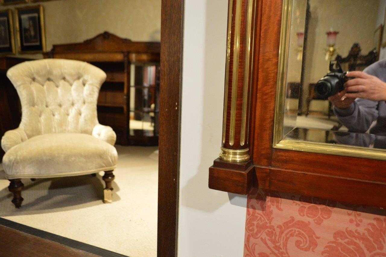 A fine quality mahogany and brass French over-mantle mirror. Having a mahogany and brass moulded cornice above an inverted breakfront frieze and a rectangular bevelled mirror plate with a brass moulded edge. Flanked by half round mahogany and brass