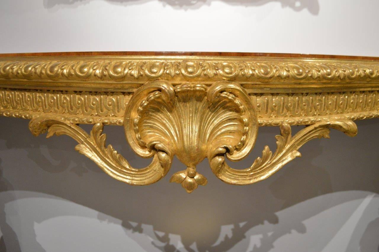 A superb 19th Century French baroque style gilt-wood serpentine console table. The top of serpentine outline veneered in beautifully figured satinwood with rosewood banding and marquetry inlaid anthemions. With an acanthus carved gilt-wood moulded