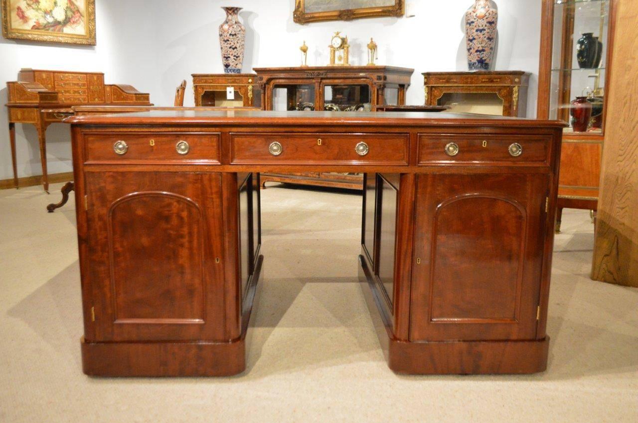 A Beautiful mahogany Victorian Period antique partners desk. Having a mahogany rectangular top with rounded corners and an inset olive green gilt and blind tooled leather writing surface. One side of the desk with an arrangement of nine mahogany