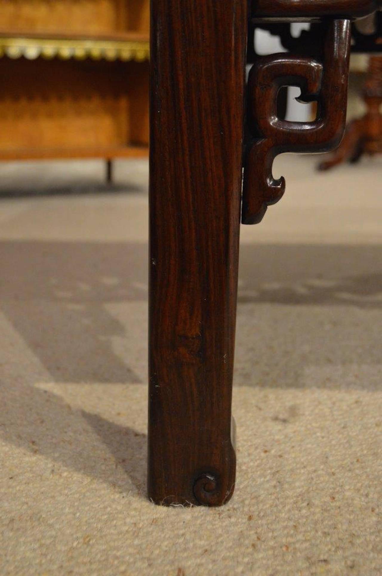 A Chinese Hongmu hardwood Kang coffee table. Having a rectangular top with cleated ends and a central hardwood panel, above a beautiful pierced fretwork frieze, repeated on the opposite side and both ends. Supported on traditional Chinese hardwood