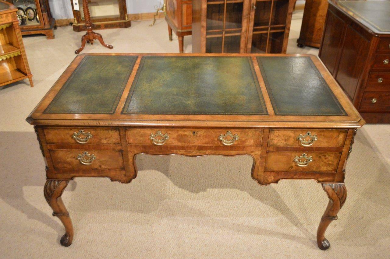Antique burr walnut and walnut writing table by Maple & Co Of London. Having a rectangular top with canted corners with three inset green leather panels with gilt and blind tooled detail and with a walnut cross banded border. The five oak lined