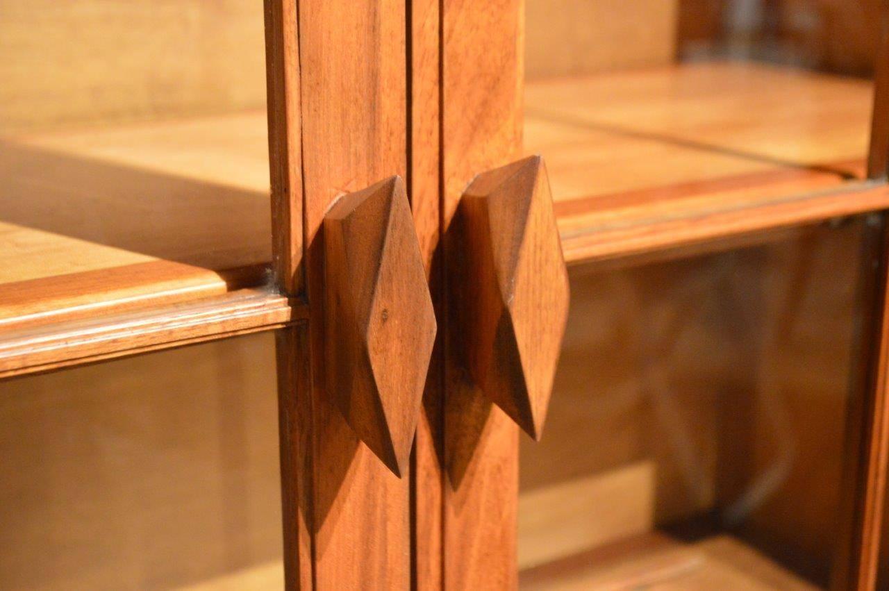 A walnut Arts & Crafts period bookcase by The Brynmawr Furniture makers. The upper section having a raised chamfered galleried back above a solid walnut rectangular top with two walnut glazed doors enclosing a shelved interior. The lower section