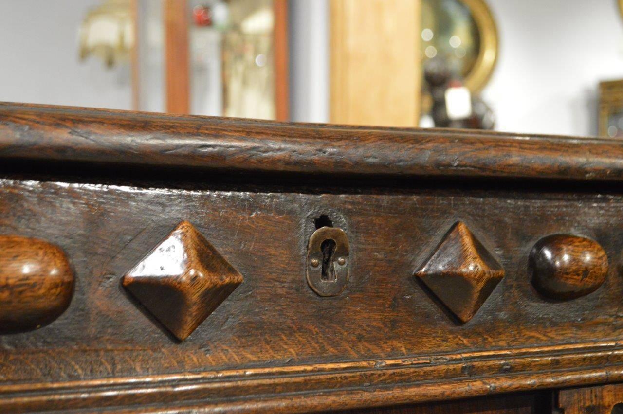 An Oak Jacobean period antique coffer. Having a three plank rectangular hinged top opening to reveal a storage area. With a wonderful front having a mixture of geometric and split baluster mouldings and with a finely carved arched central panel.