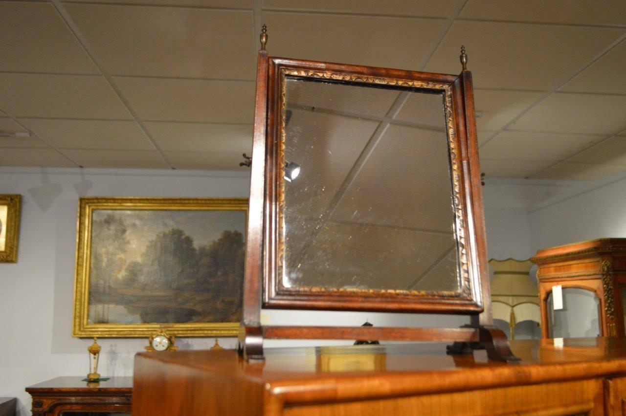 A mahogany George III period antique dressing mirror. The rectangular adjustable mahogany mirror with gilt slip and supported on a mahogany frame surmounted with finials, English, circa 1780.

Dimensions: 16