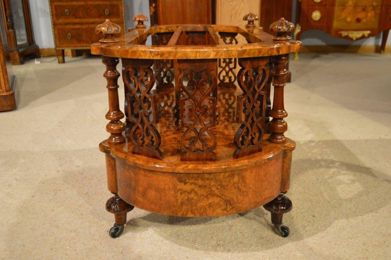 A burr walnut Victorian period antique canterbury. Of oval form with bowed ends veneered in burr walnut and having finely carved walnut finials, with three divisions and with fine pierced fretwork panels. The base veneered in beautifully figured