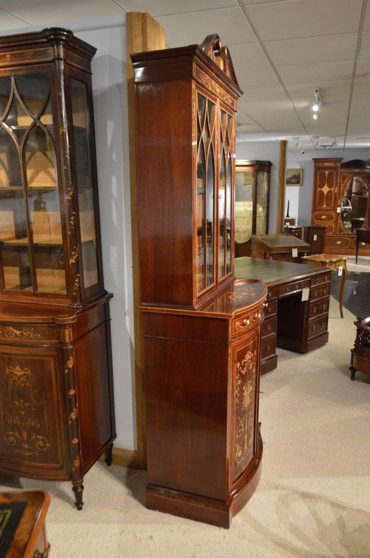 A stunning quality mahogany late Victorian period bookcase by Edwards & Roberts of London. The upper section with a broken swan neck pediment having inlaid paterae and urn inlaid frieze, above twin astragal glazed doors with sycamore and ebony