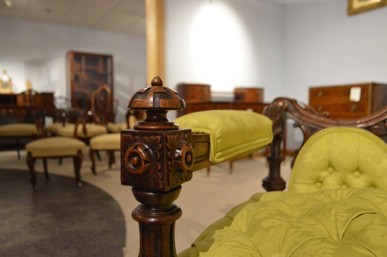 A superb quality carved walnut Victorian Period antique sofa/chaise newly re-upholstered in Sanderson's chartreuse silk. Having a shaped back finely carved with harebells, finials and acanthus leaves. With a central deep buttoned back support