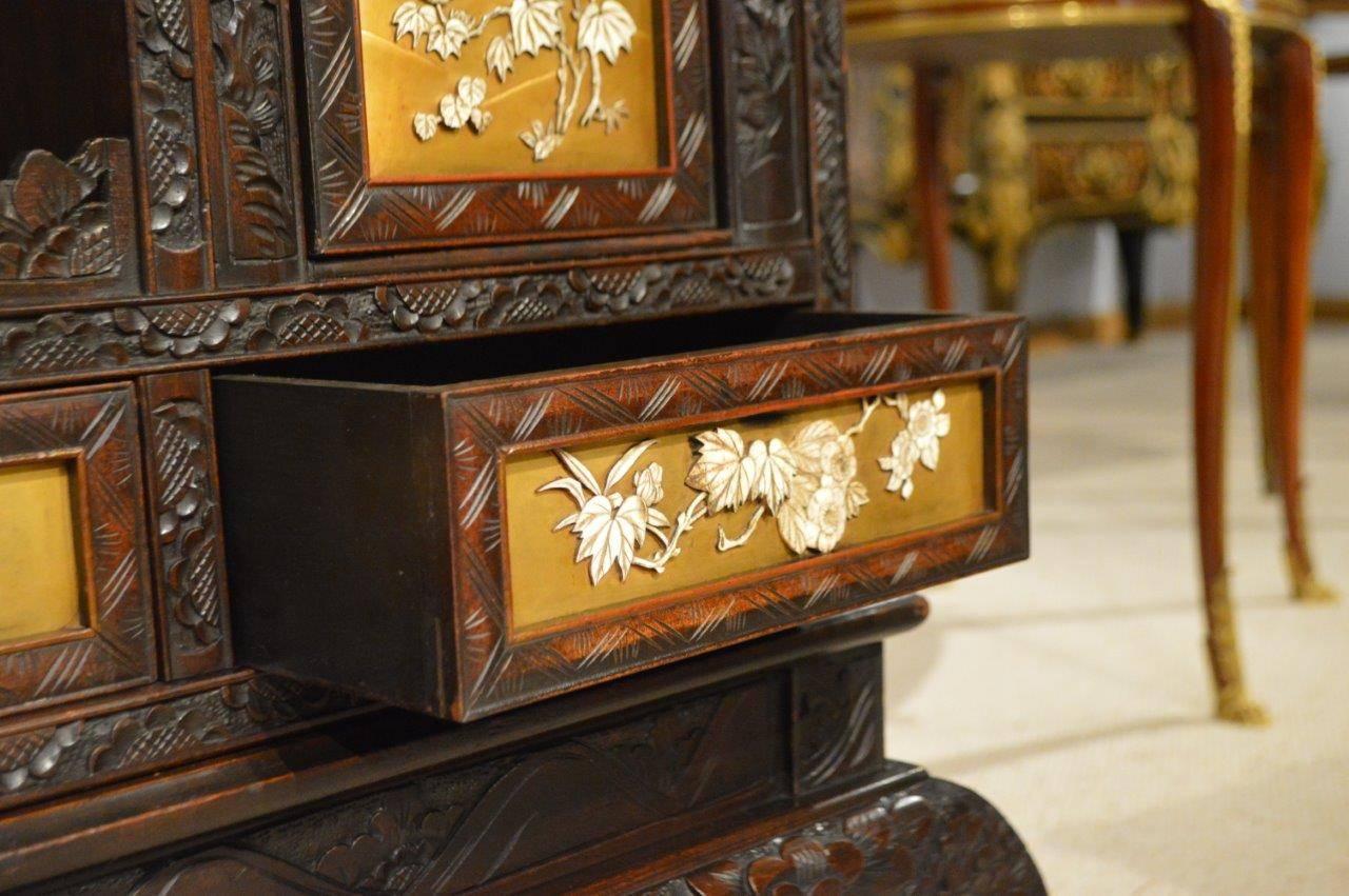 A Japanese Meiji period carved shodana with gold lacquer on-laid panels. Having a typical oriental carved cornice above the cabinet section, featuring an arrangement of sliding doors, cupboards and drawers, each with gold lacquer panels and on-laid