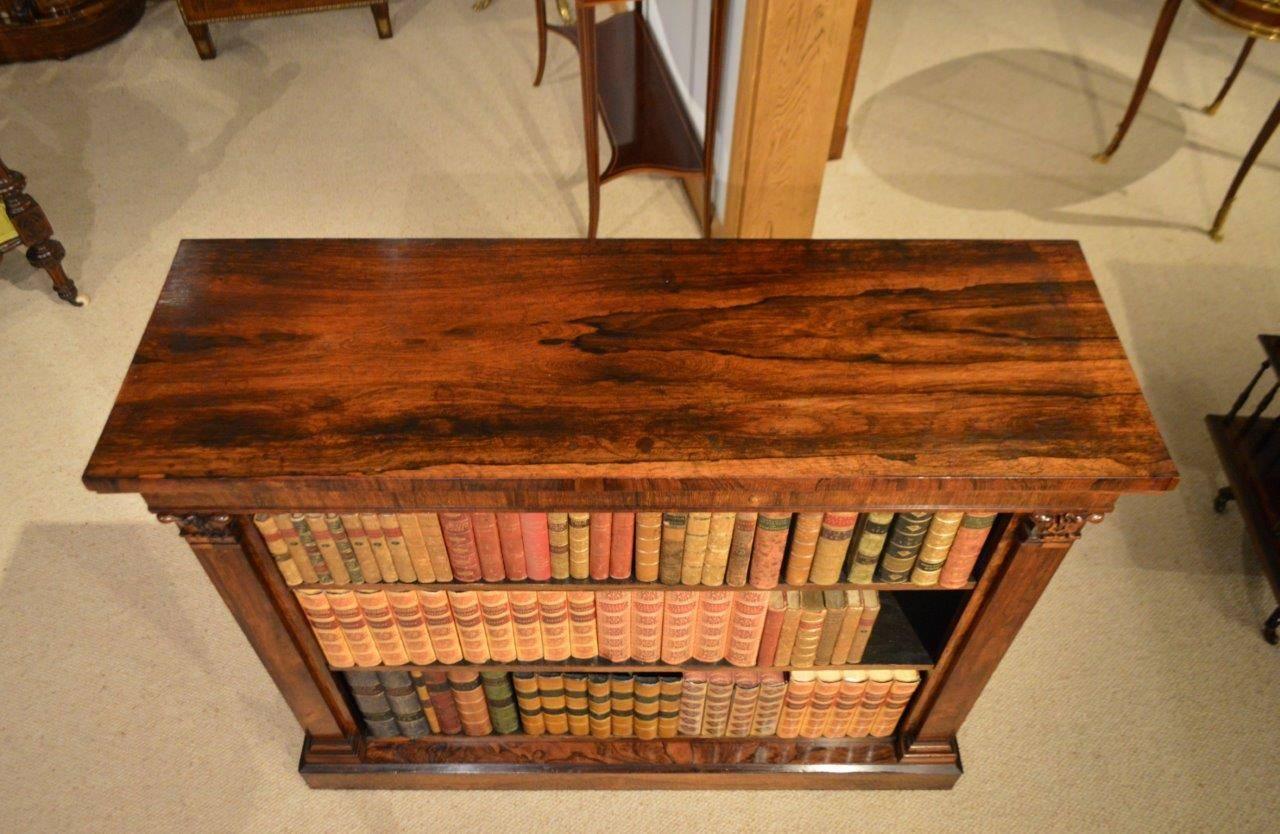 A rosewood William IV period antique open bookcase. Having a rectangular top veneered in well figured rosewood above a rosewood frieze with banded moulding. The two adjustable shelves flanked by raised pilasters with carved capitols and stepped