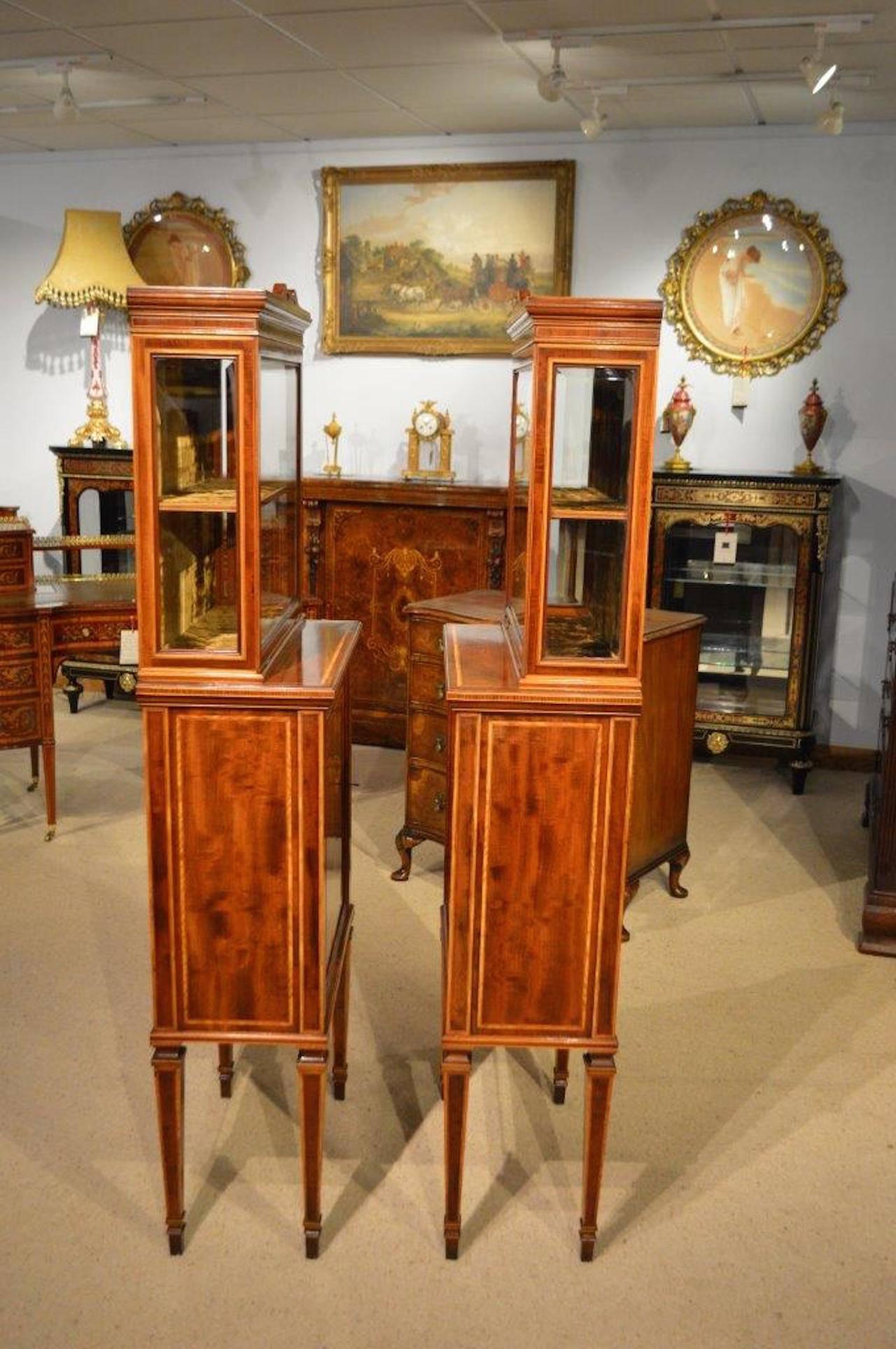 A fine quality pair of Edwardian Period fiddleback mahogany inlaid cabinets. Each with a glazed bevelled glass upper display section with a velvet lined shelved interior and bevelled glazed ends. The lower sections constructed using the finest