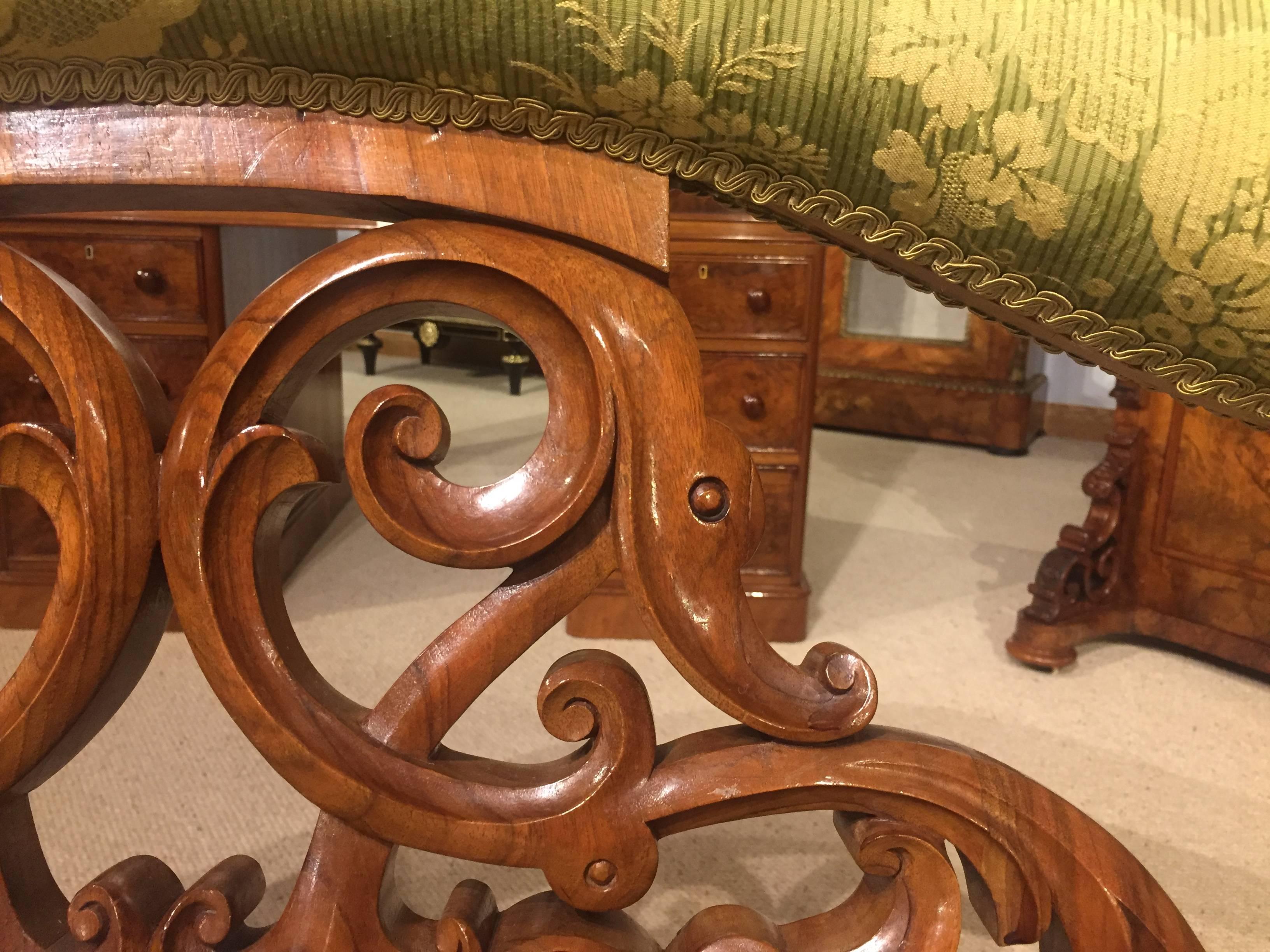 A beautiful quality carved walnut Victorian period boudoir sofa. Having a shaped back with an upholstered padded top rail above a fine carved elaborate pierced backs plat, with acanthus carved shaped supports above the bowed end curved sprung seat,