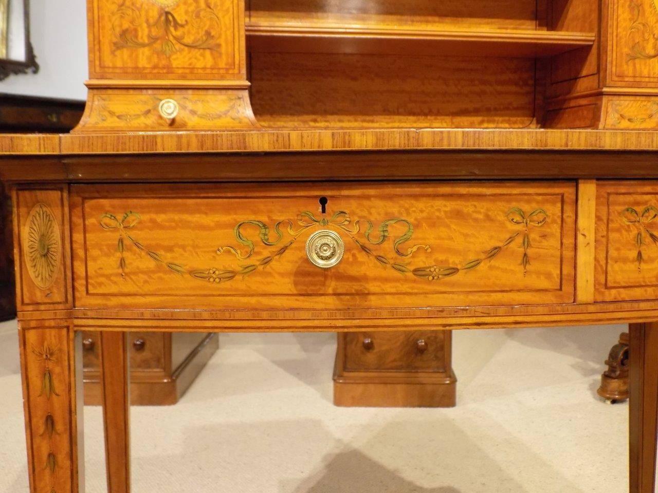 A fine quality satinwood Victorian period ladies writing table. The upper section having brass galleries, two open shelves, two marquetry inlaid compartments and twin shaped small drawers with fine ribbon, swag and urn inlaid detail. The lower