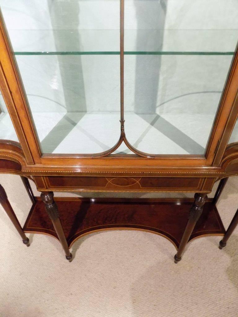 A fine quality mahogany inlaid Edwardian period antique china cabinet. The upper section has a domed and moulded cornice with a plum pudding mahogany frieze, above the central astragal glazed door which opens to reveal a silk lined and glass shelved