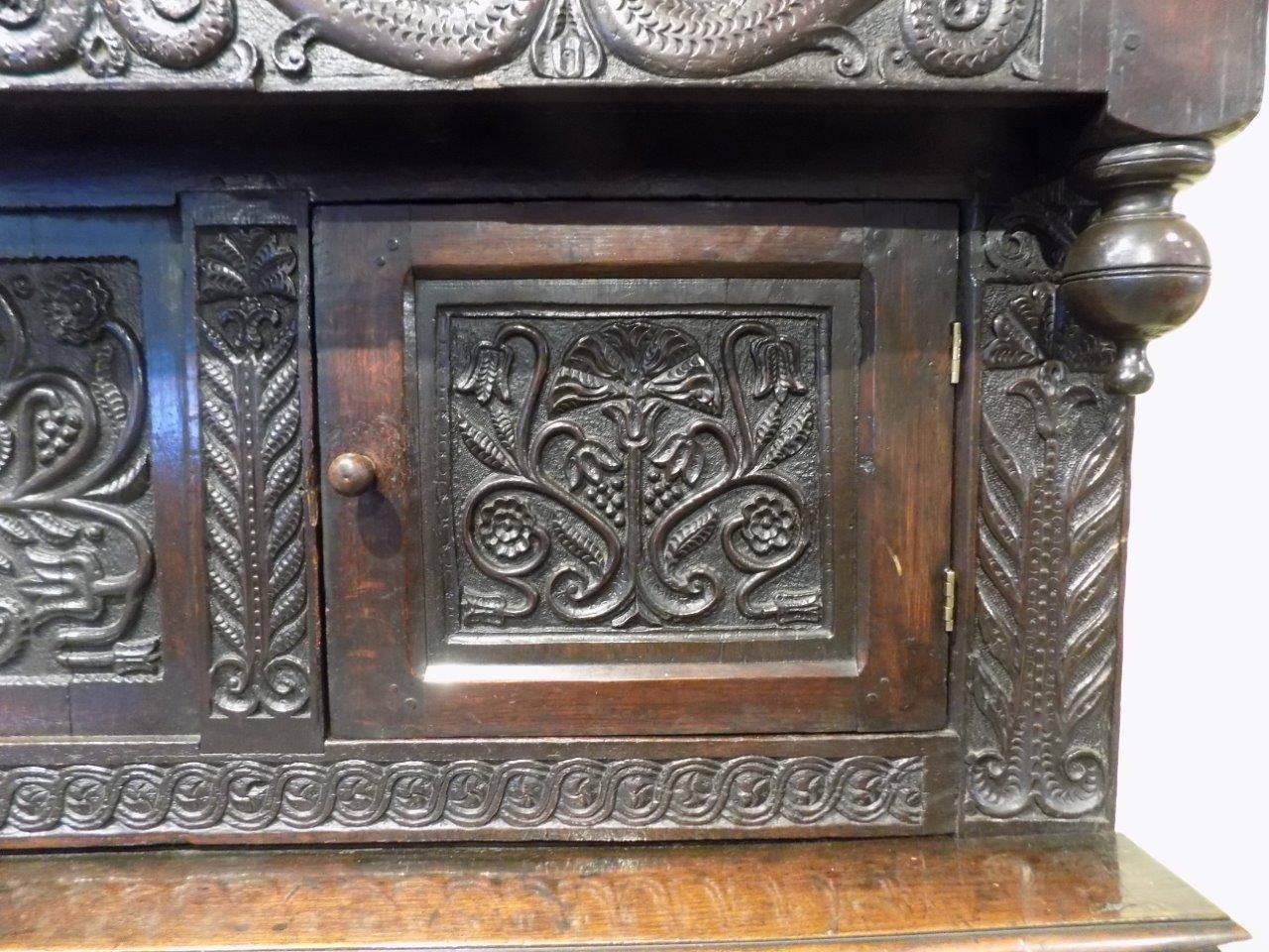 A rare late 17th Century Westmorland antique oak court cupboard. The upper section has a canopy with beautifully carved detail above two panelled doors and a central carved panel. The lower section having twin panelled doors with typical Westmorland