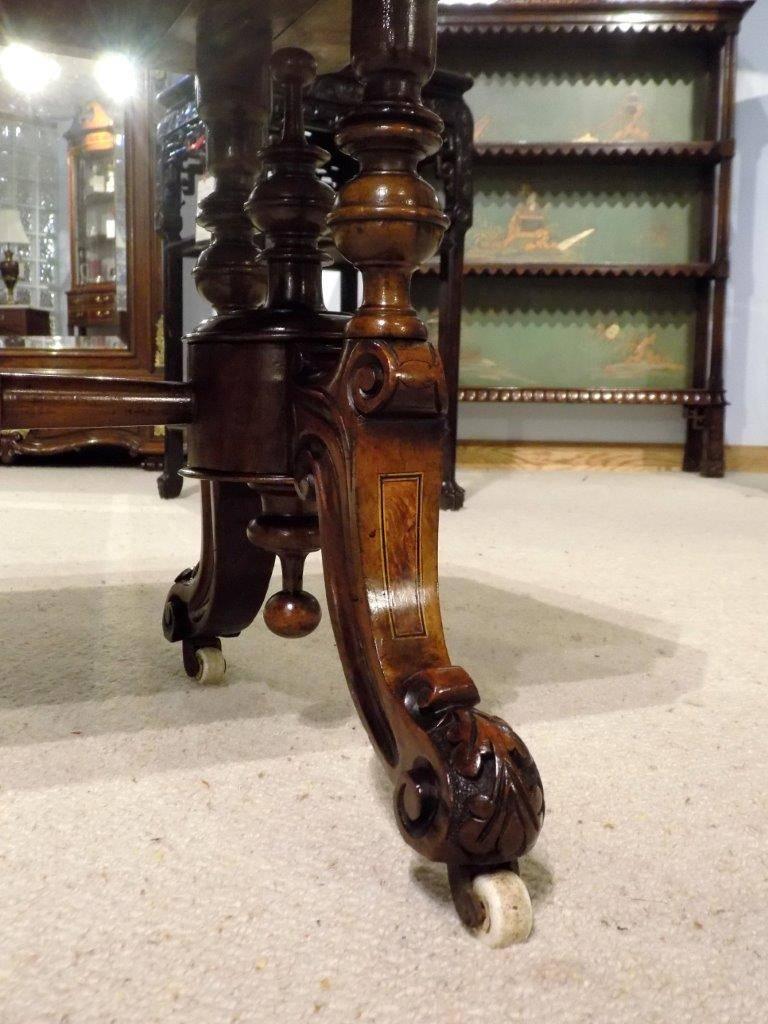 A burr walnut and amboyna inlaid Victorian period antique coffee table. Having a rectangular top with canted corners veneered in beautifully figured burr walnut with amboyna banding and an angular moulded edge. Supported on four turned columns,