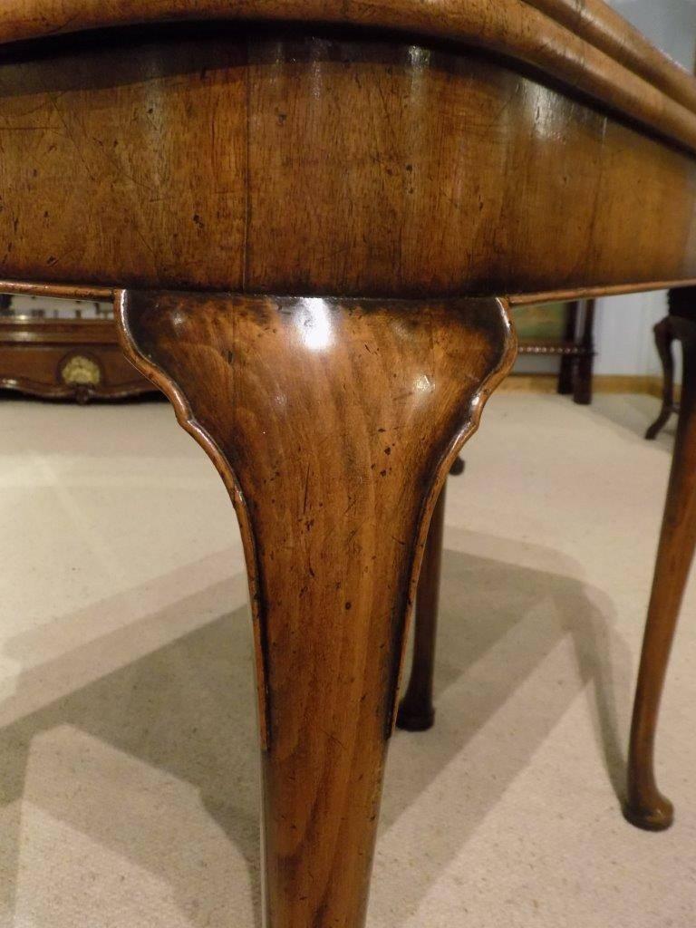 A burr walnut and walnut George I style antique fold over card table. Having a rectangular top with rounded corners veneered in burr walnut and crossbanded in walnut, which turns and opens to reveal a fine needlepoint floral material with a walnut