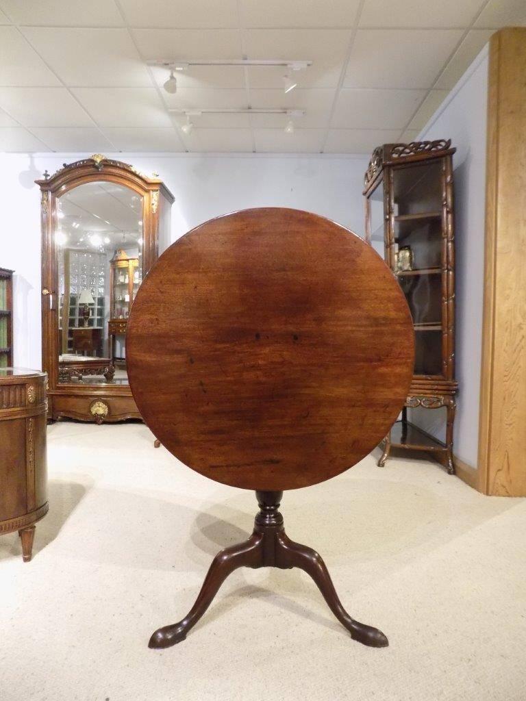 A mahogany George III period tilt-top tripod table. The circular Cuban mahogany one piece top raised on a baluster column with three elegant cabriole supports and pad feet, English, circa 1770-1780

Dimensions: 27" high x 28"