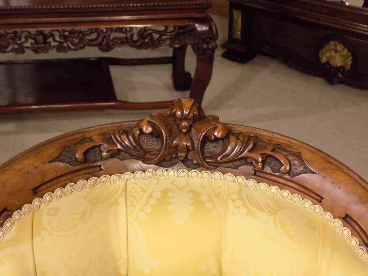 A good carved walnut Victorian period antique armchair. The deep buttoned shaped back above a generous sprung seat and serpentine seat rail. Having open padded arms, the whole raised on floral carved cabriole supports with brass and porcelain