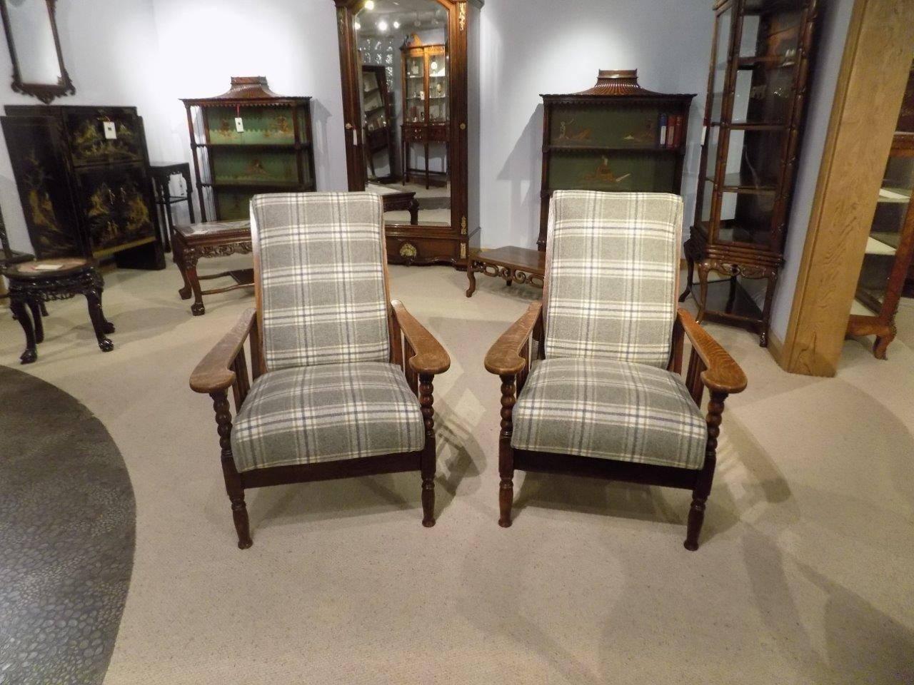 A good pair of oak Arts & Crafts period reclining armchairs newly re-upholstered in moon wool fabric. Each with an angular reclining back and seat upholstered in moon check wool with a matching herringbone wool to the backs and sides of the
